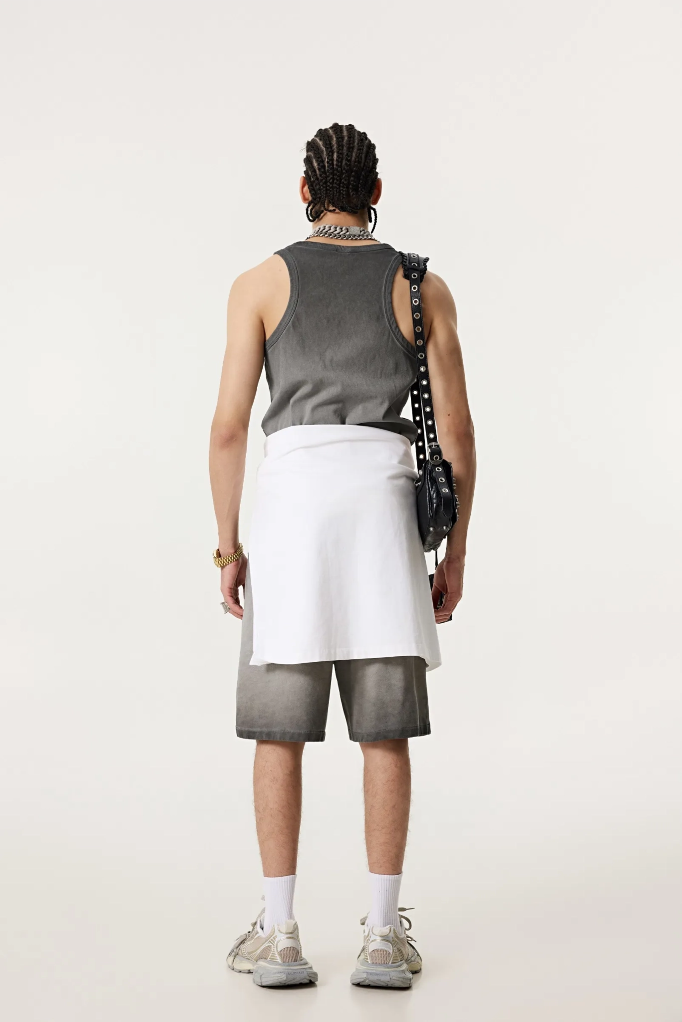 Person wearing a gray sleeveless top, white skirt, and shorts on a plain background