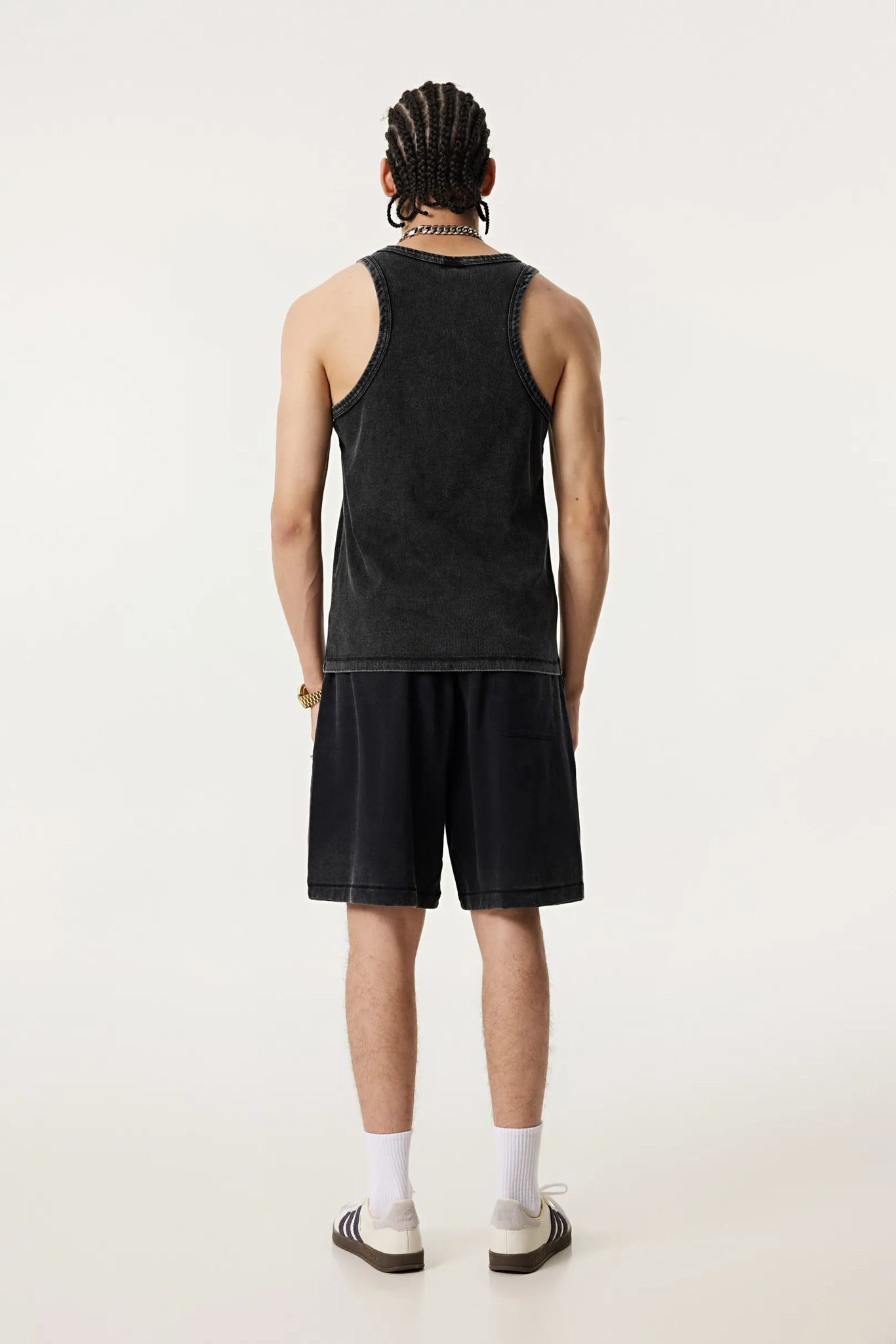 Person wearing a black tank top and shorts on a white background