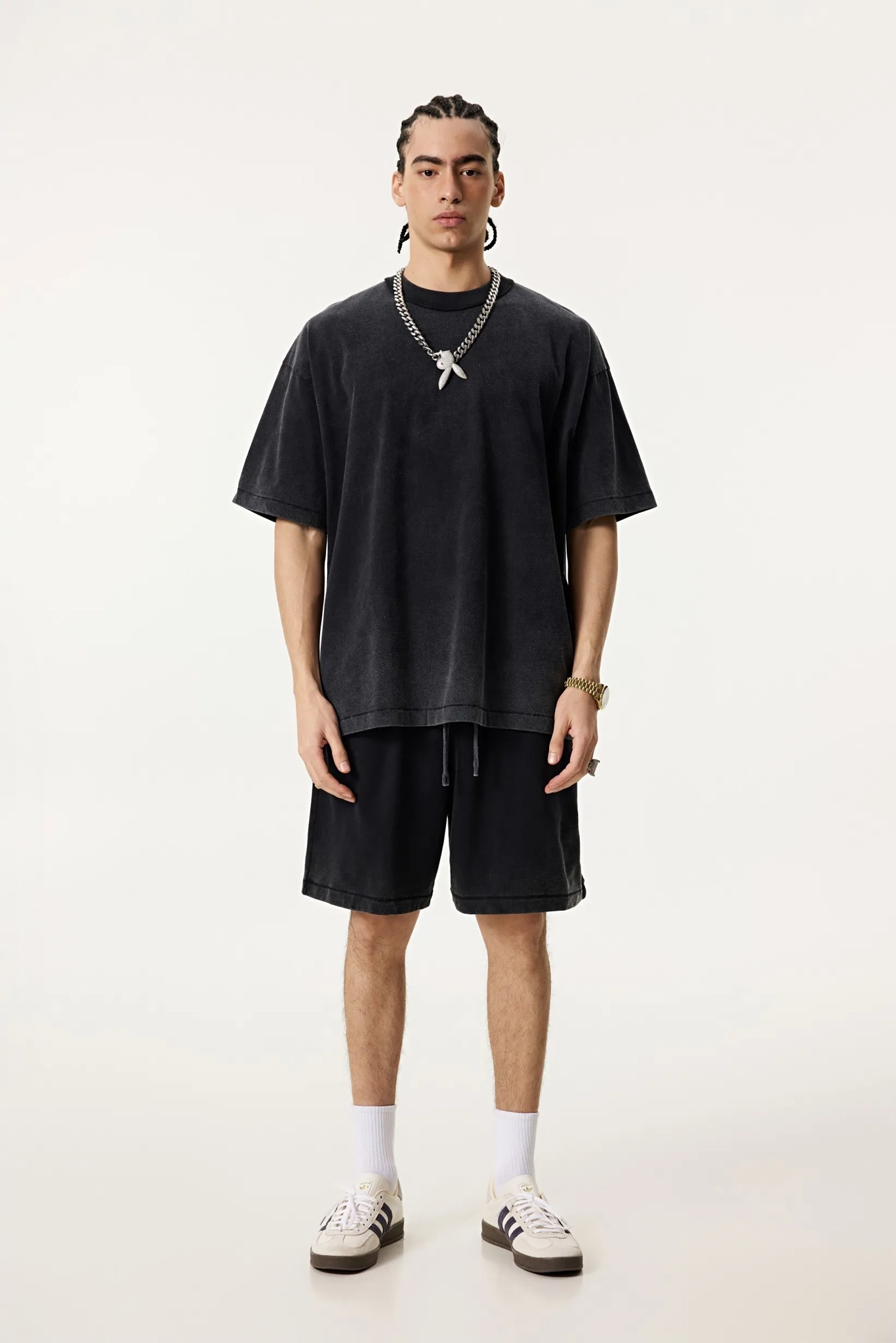 Person wearing a black oversized t-shirt and shorts set on a white background