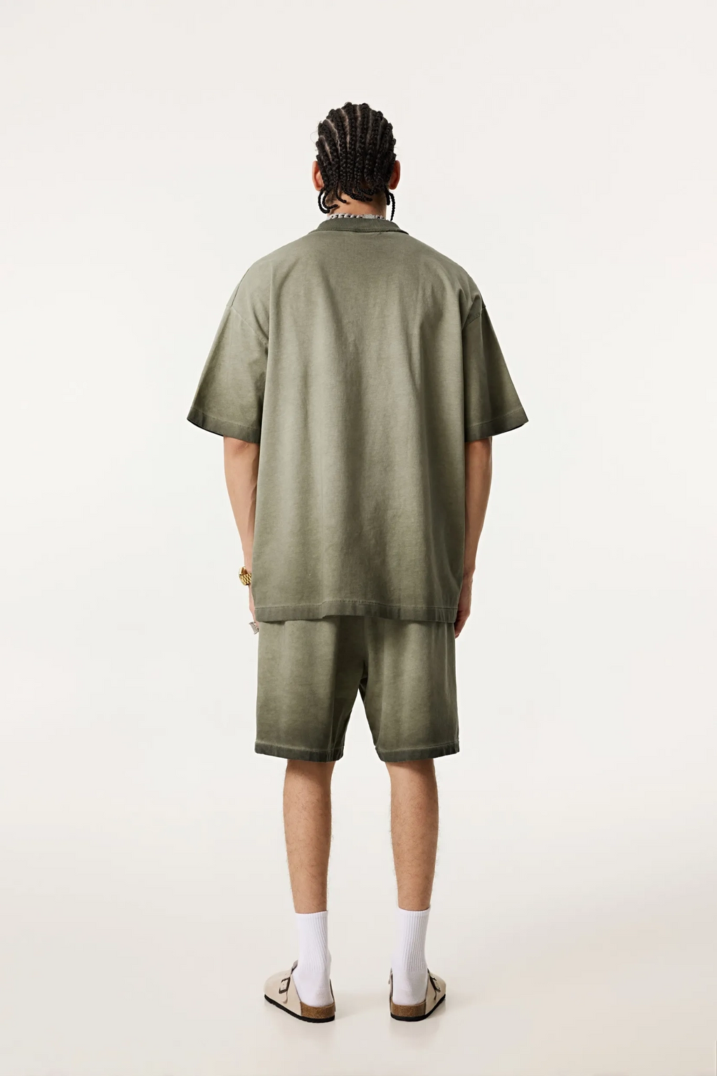 Person wearing a green outfit with shorts on a white background