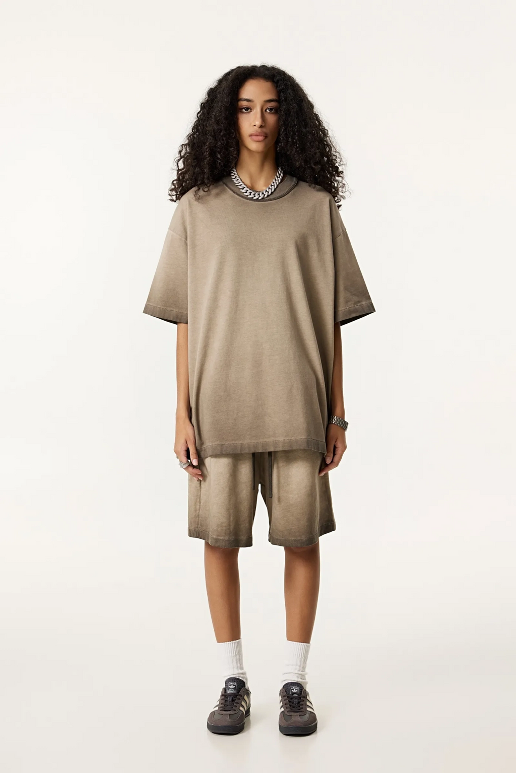 Person wearing a beige oversized sweater and shorts set on a white background