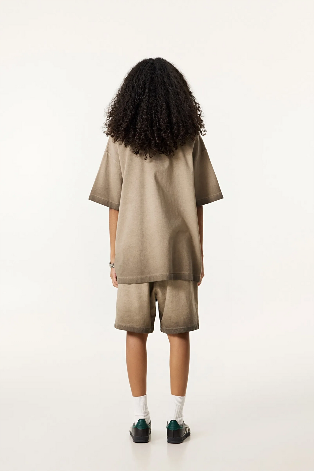 Person wearing a beige outfit with shorts on a white background