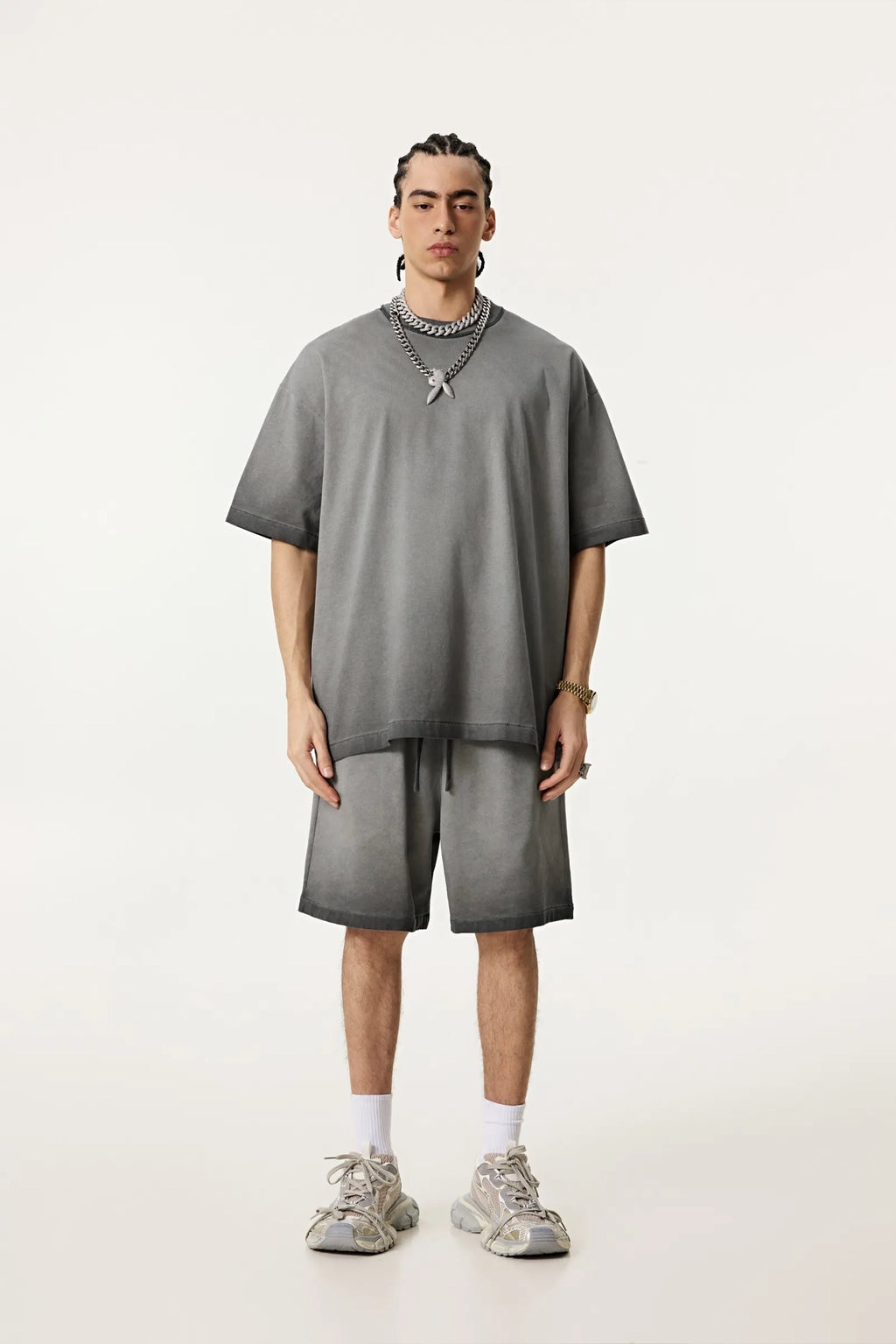 Person wearing a gray outfit with shorts and a t-shirt on a white background