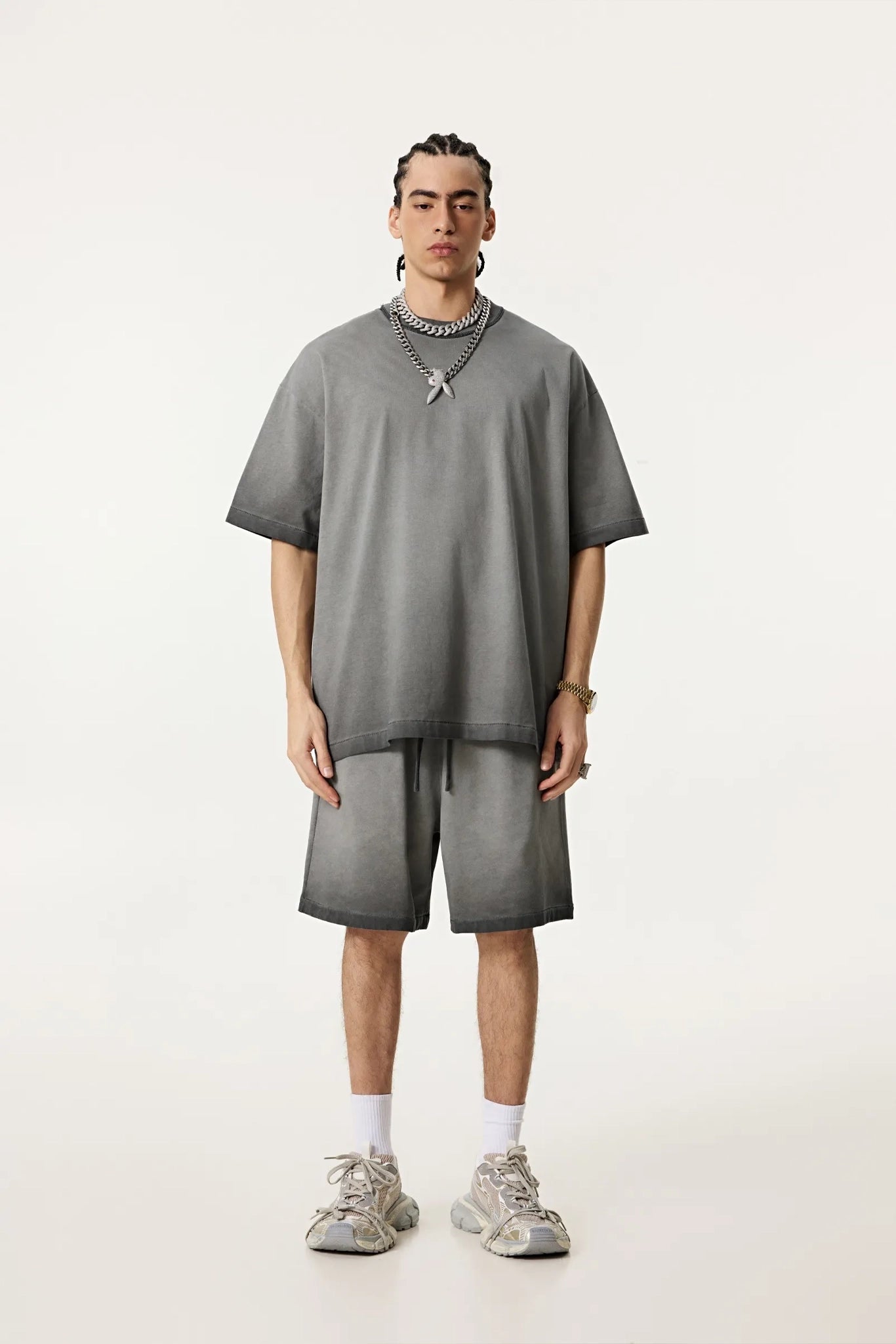 Person wearing a gray outfit with shorts and a t-shirt on a white background