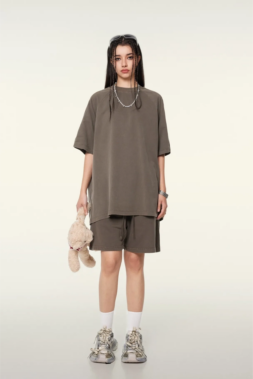 Person wearing a brown oversized t-shirt and shorts set on a white background