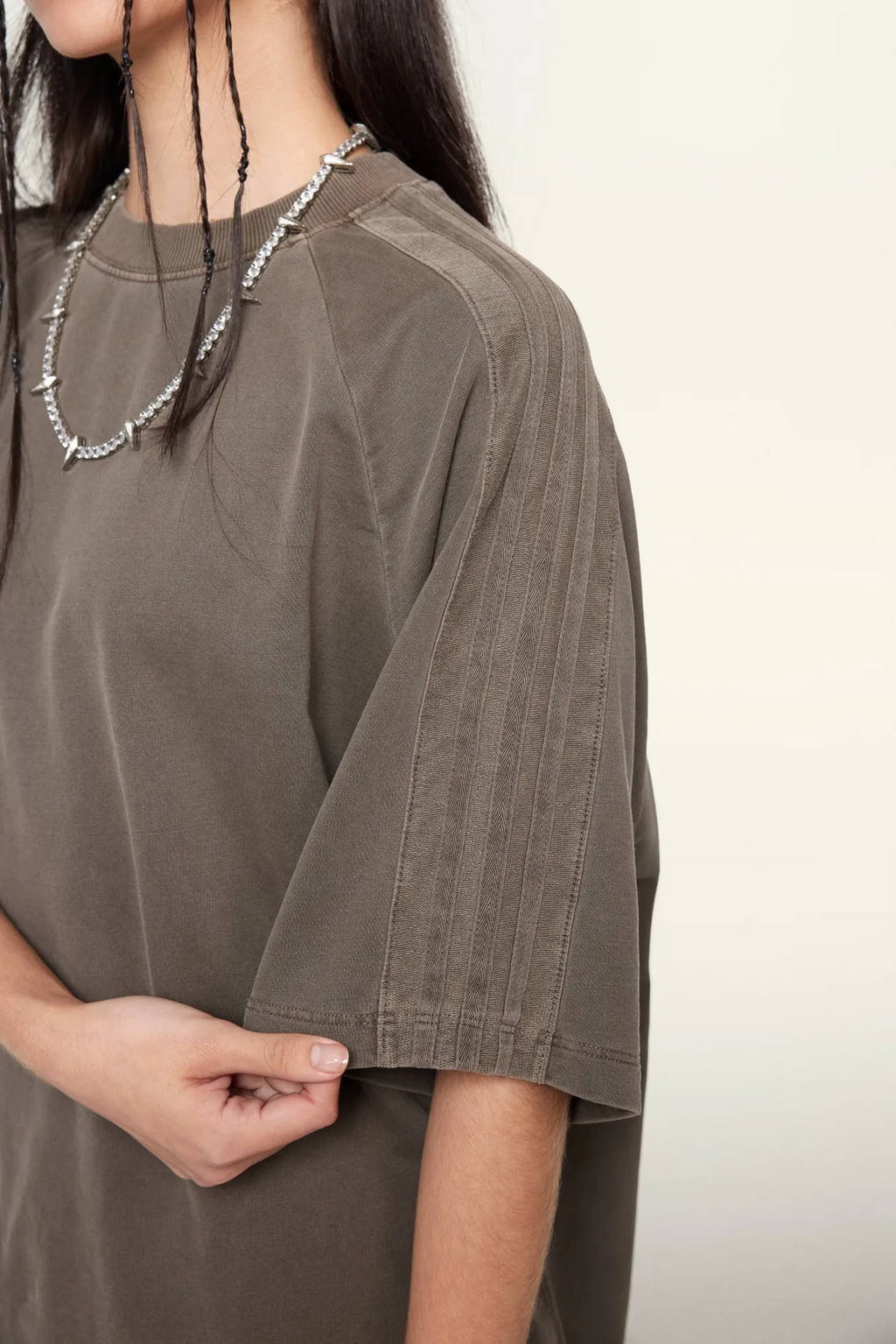 Person wearing a brown oversized t-shirt against a plain background