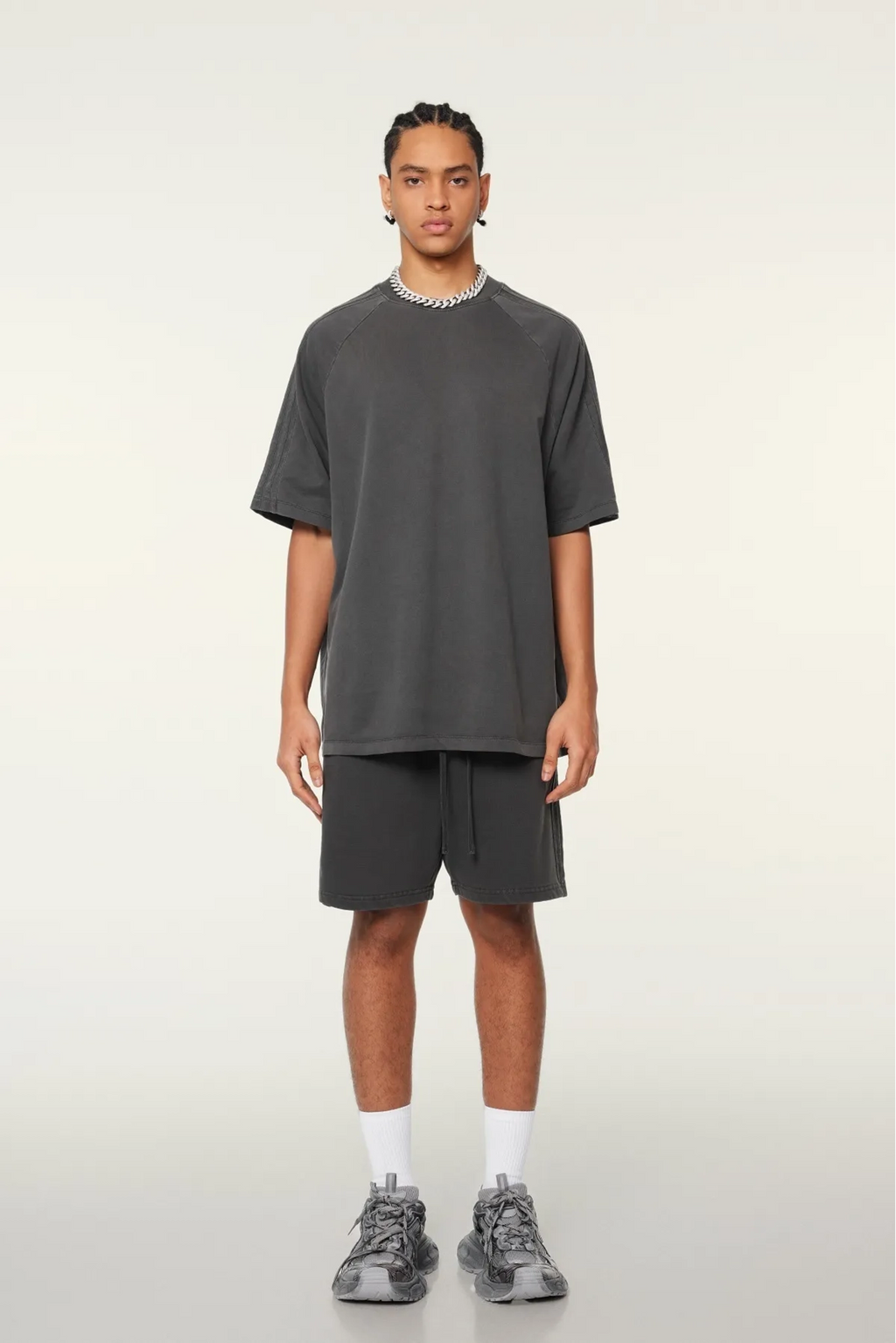 Person wearing a gray t-shirt and shorts set on a light background