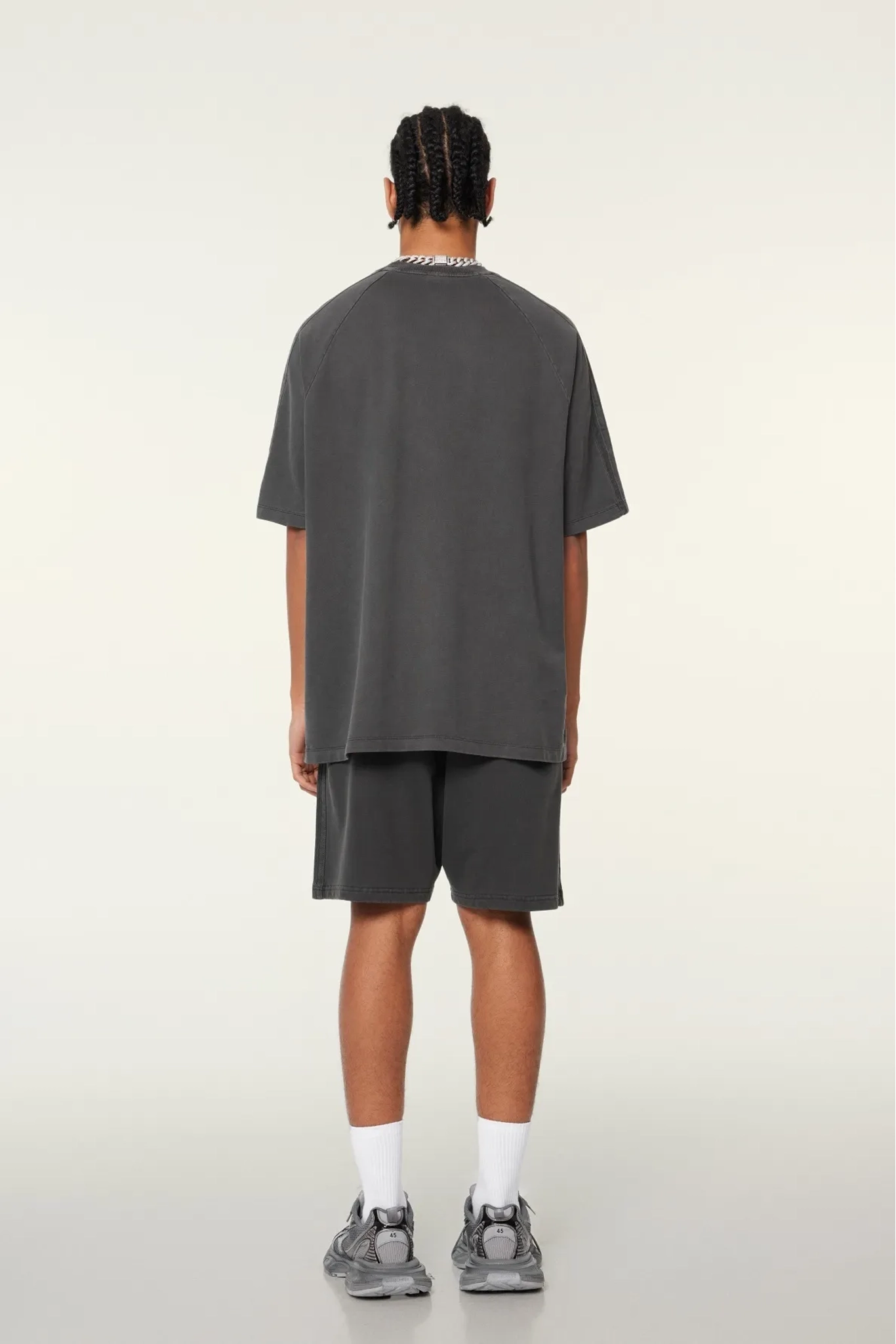 Person wearing a gray oversized t-shirt and shorts set on a white background