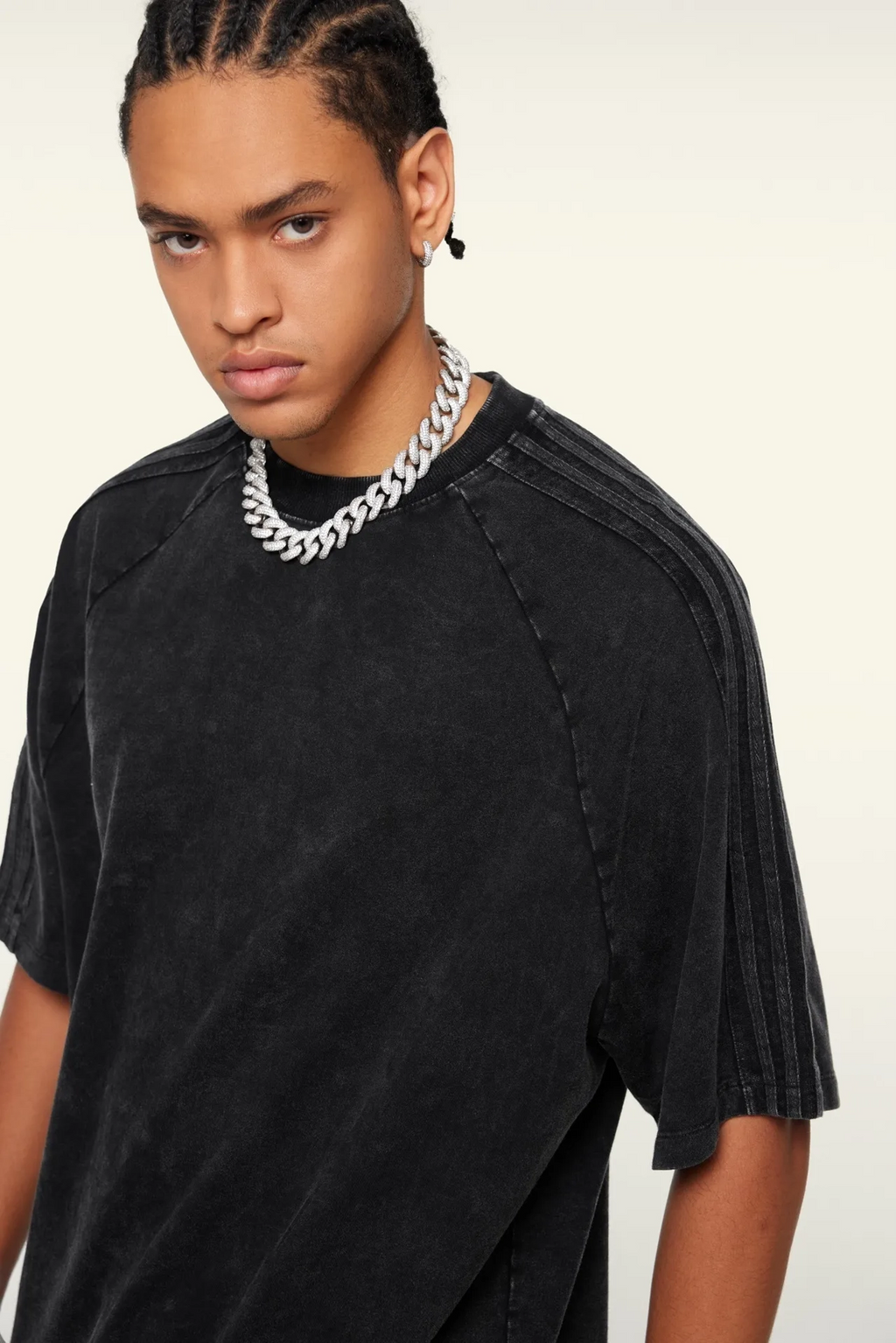 Person wearing a black t-shirt and silver chain necklace on a white background