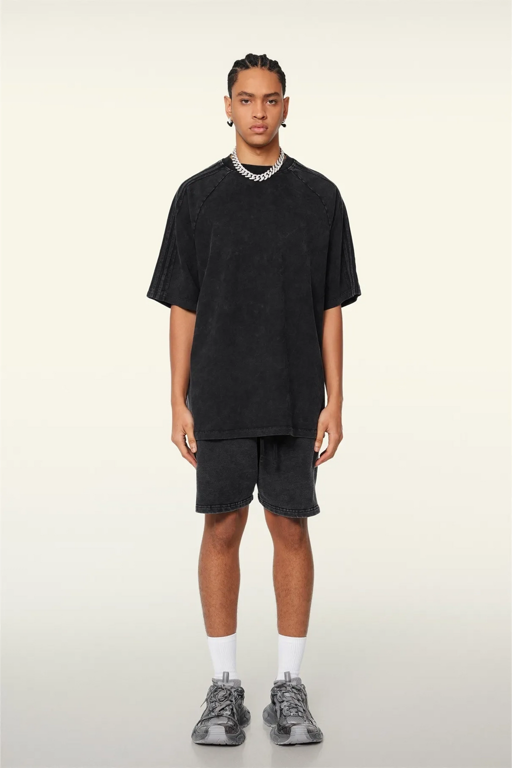 Person wearing a black oversized t-shirt and shorts set on a white background