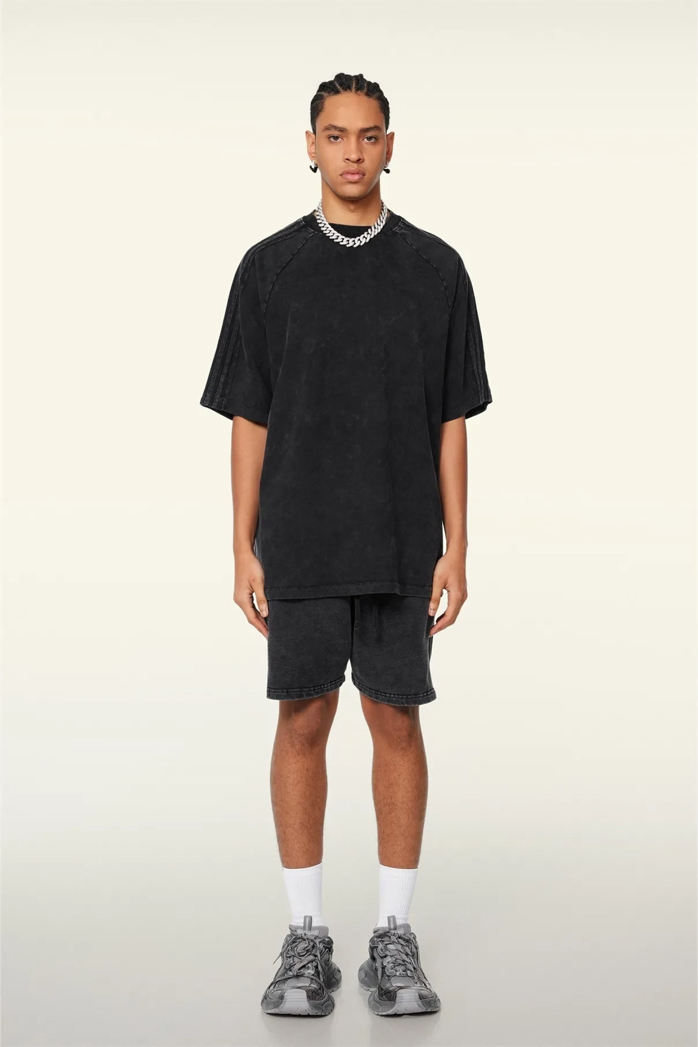 Person wearing a black oversized t-shirt and shorts set on a white background