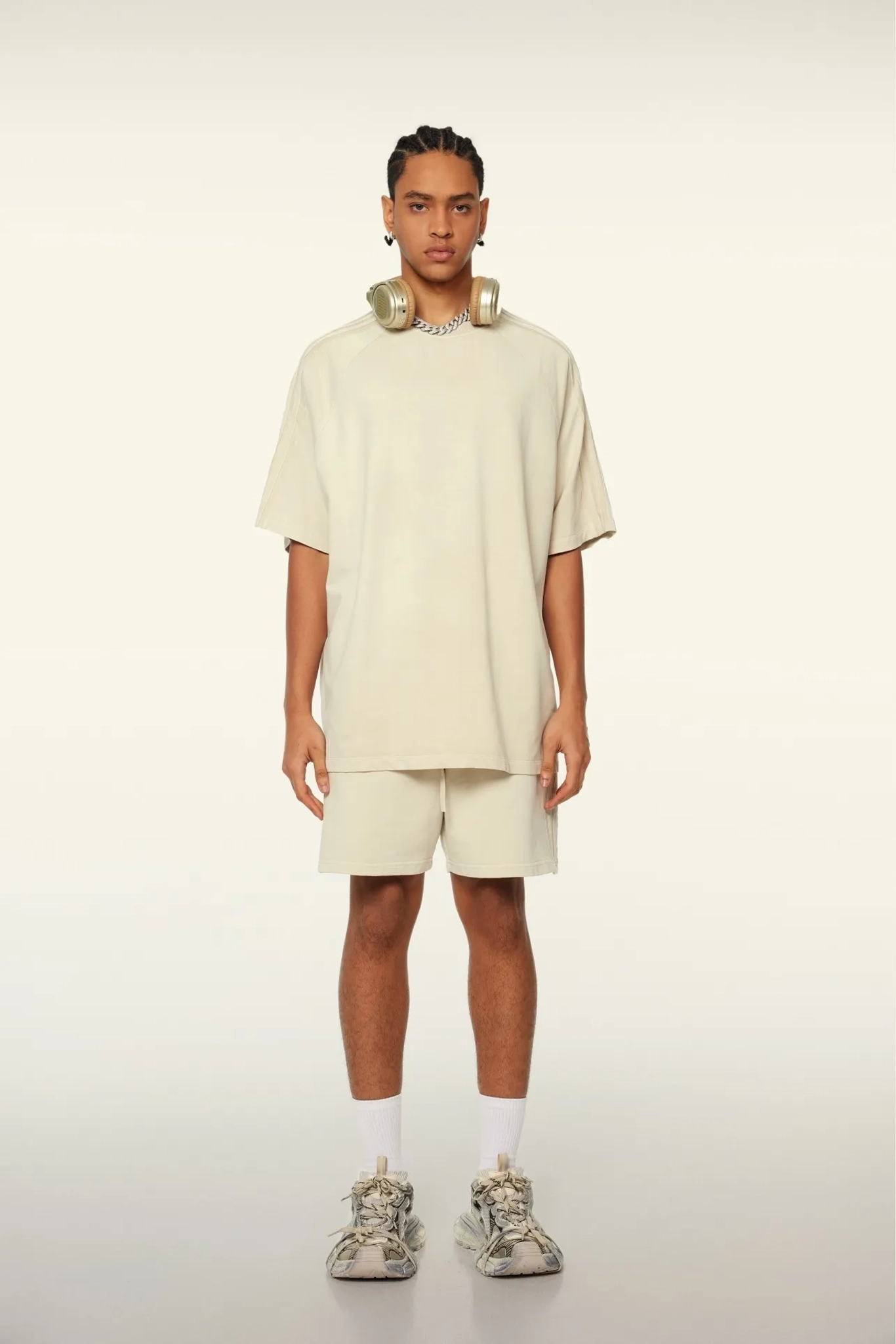 Person wearing a beige outfit with shorts and sneakers on a white background