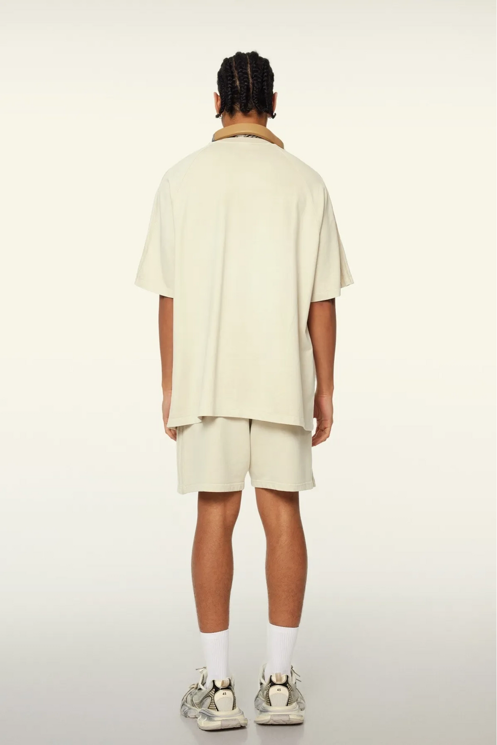 Person wearing a beige outfit with shorts on a white background