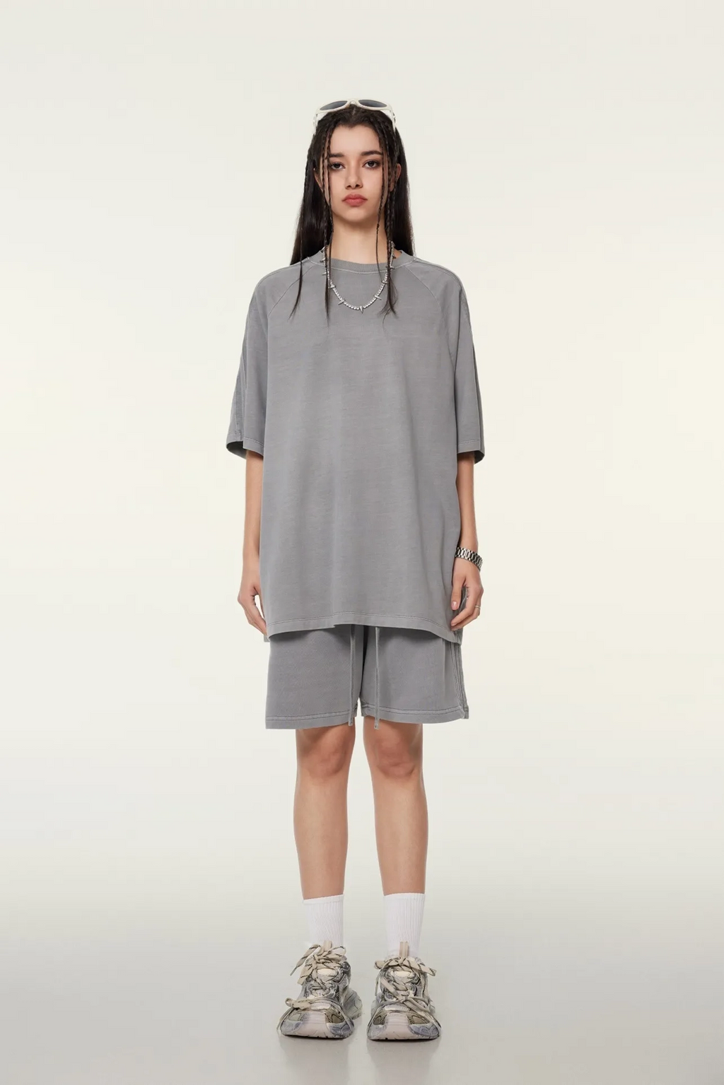 Person wearing a gray oversized shirt and shorts set on a white background