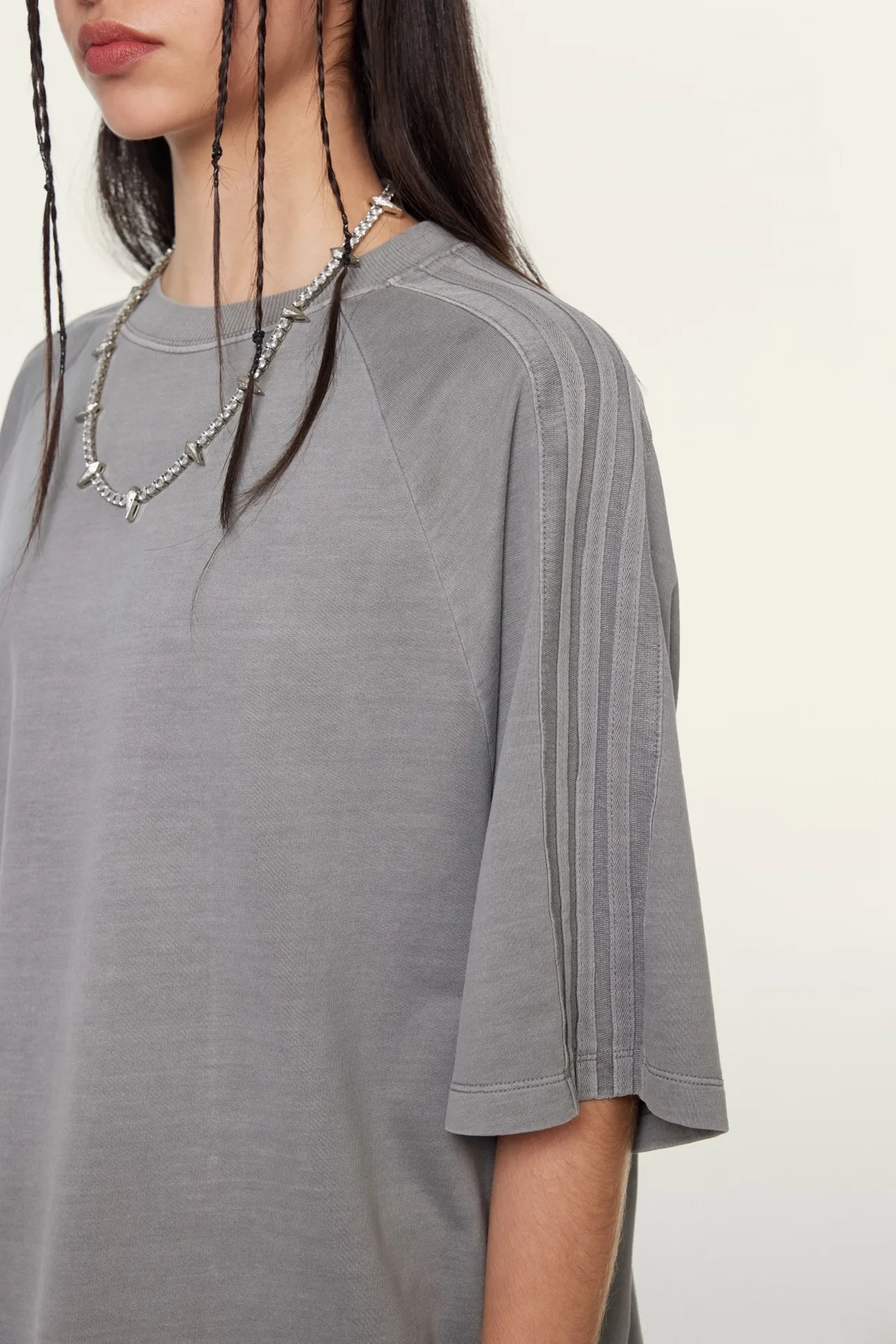 Person wearing a gray oversized t-shirt with a plain background