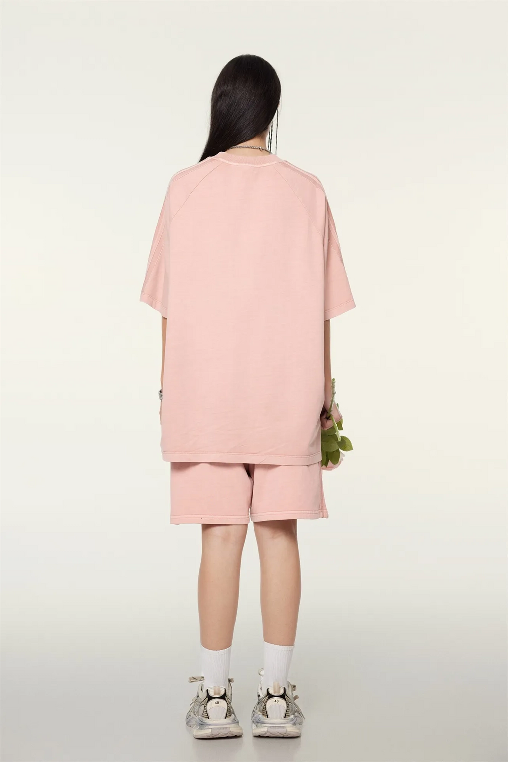 Person wearing a pink outfit standing against a white background