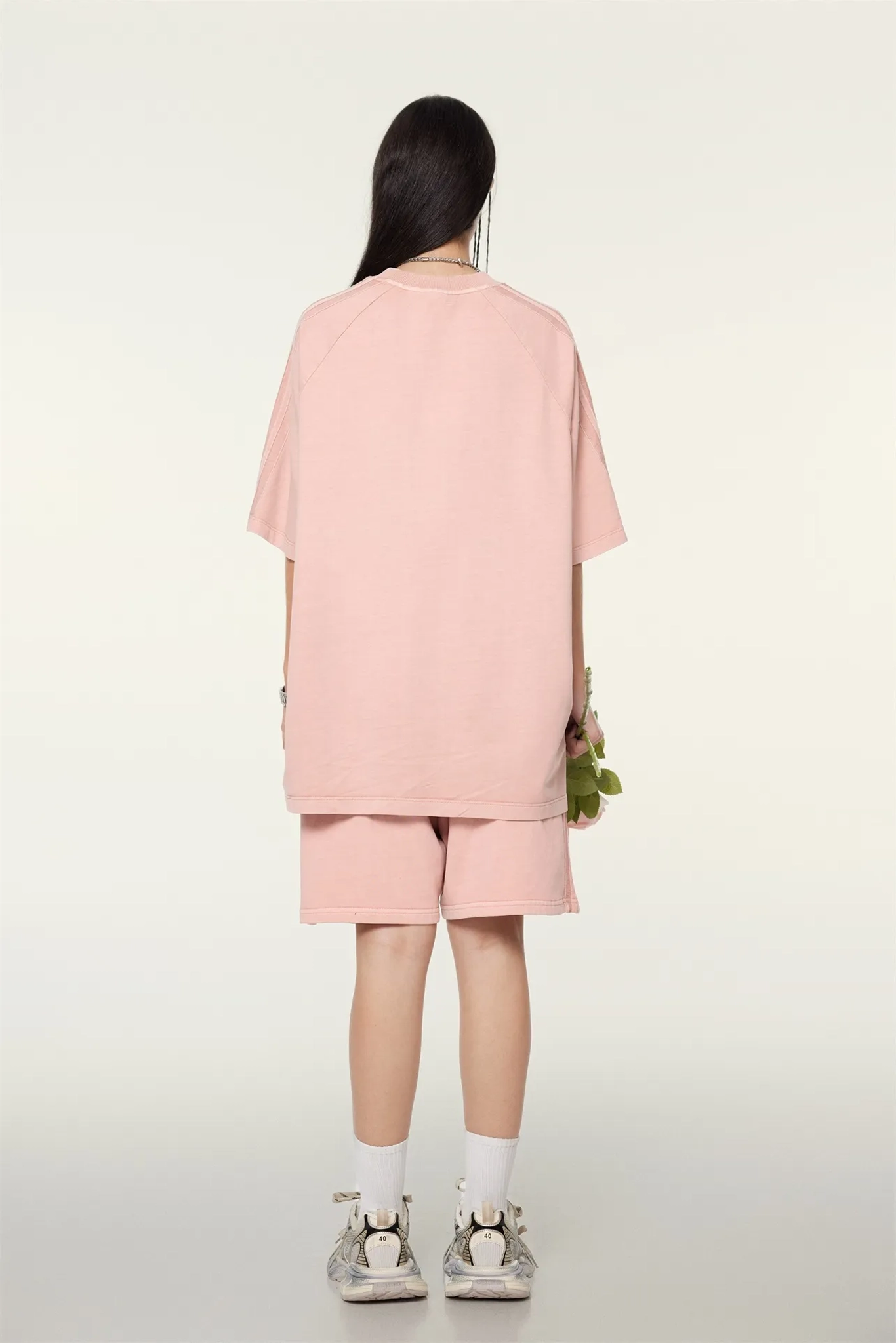 Person wearing a pink outfit standing against a white background