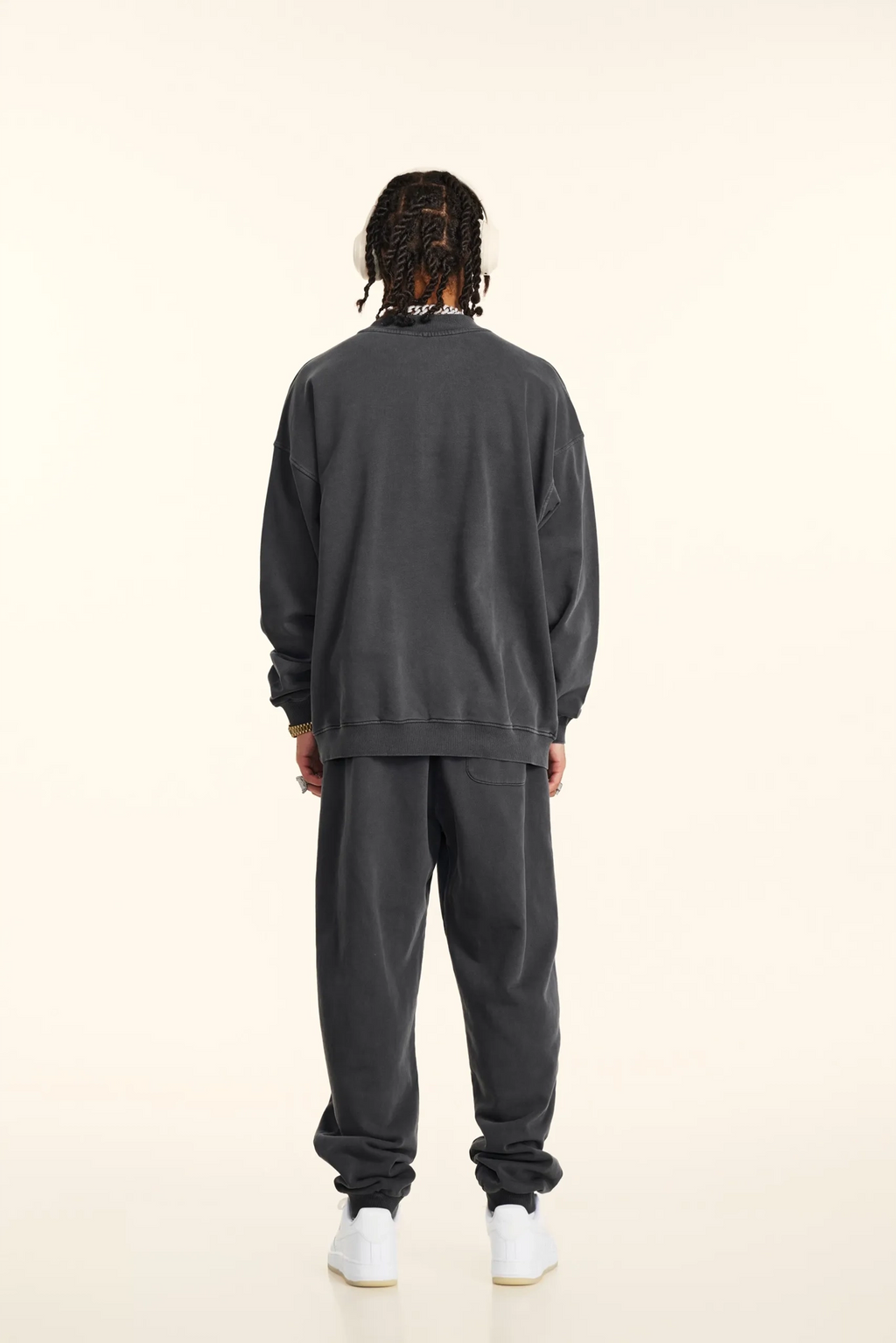 Person wearing a dark gray tracksuit on a white background