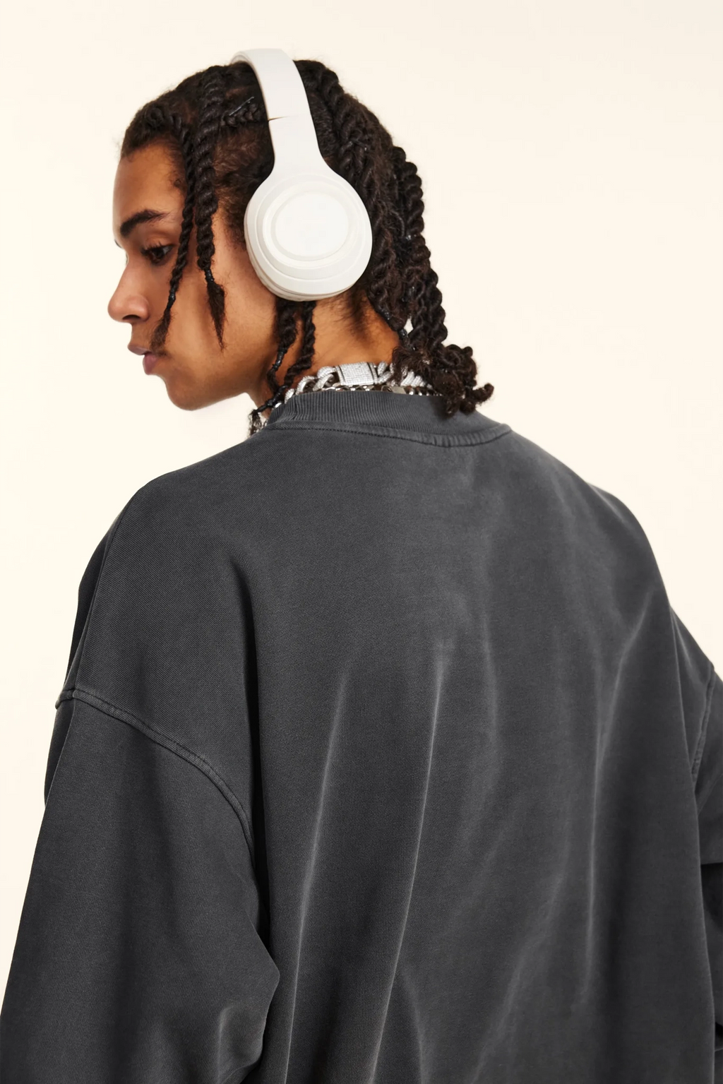 Person wearing white headphones from behind on a beige background