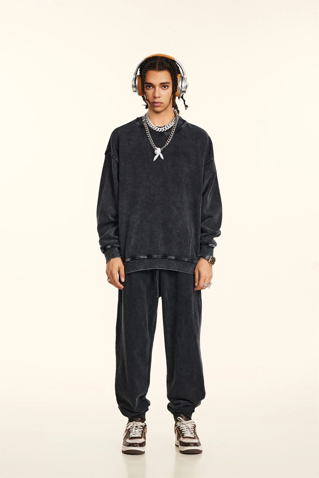 Person wearing a black outfit with headphones on a beige background