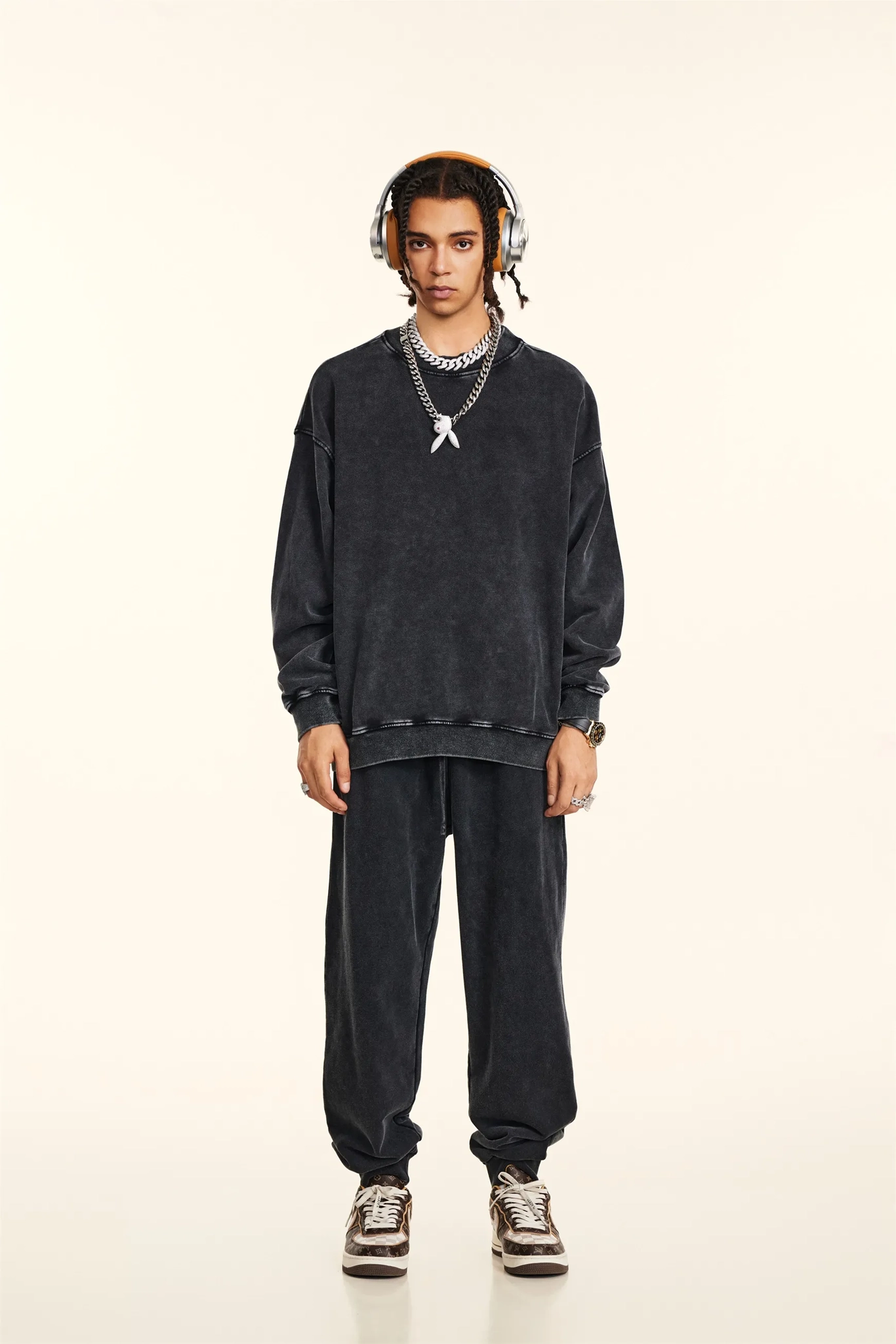 Person wearing a black outfit with headphones on a beige background