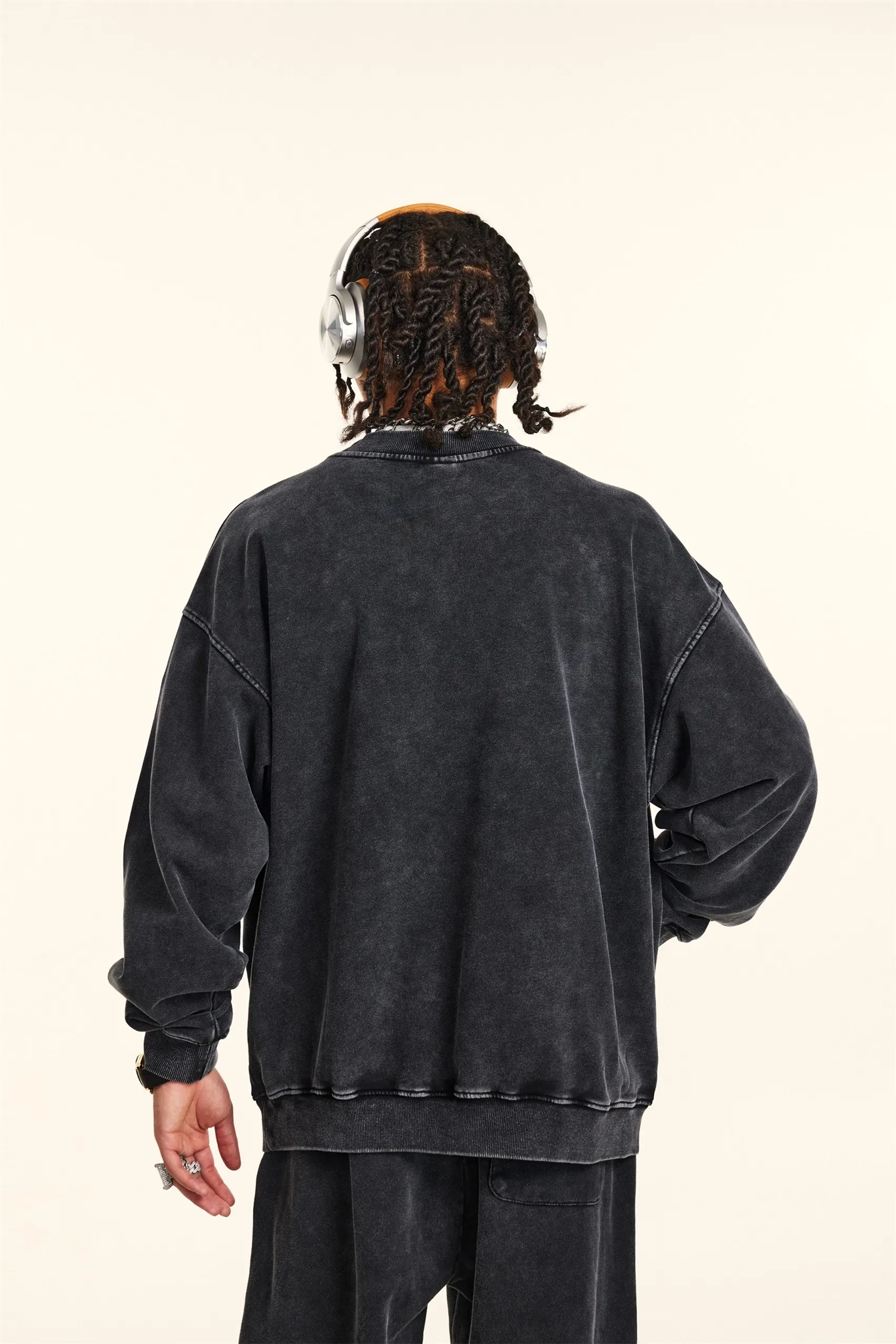 Person wearing a black sweatshirt from behind on a beige background