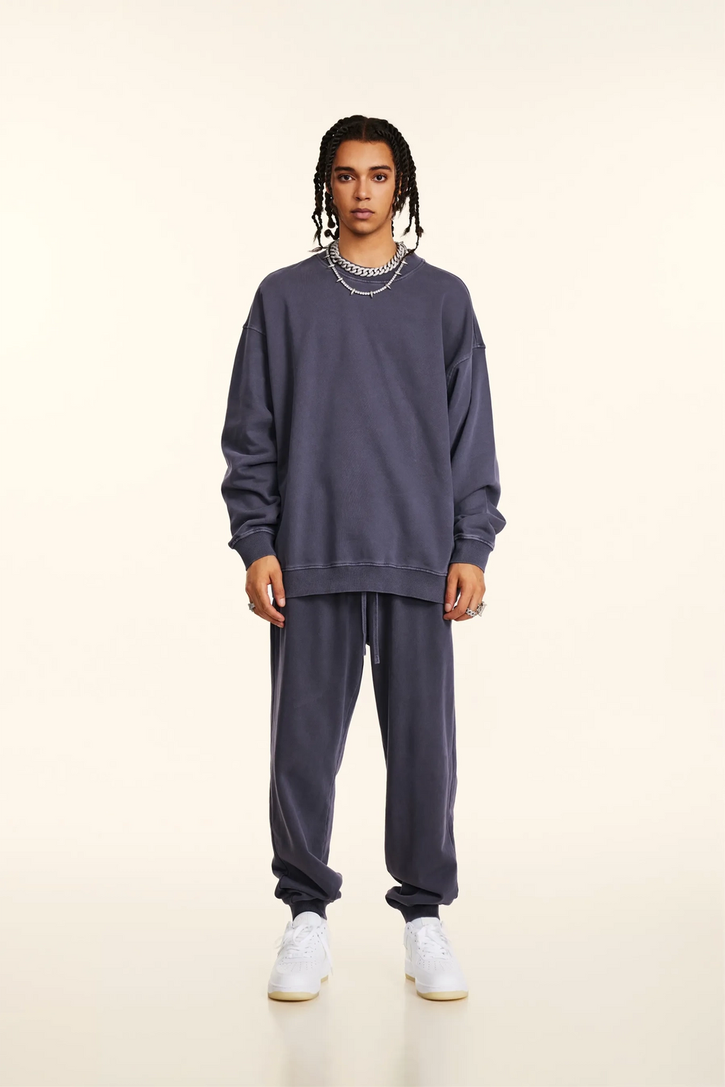 Person wearing a matching purple sweatshirt and pants set on a white background
