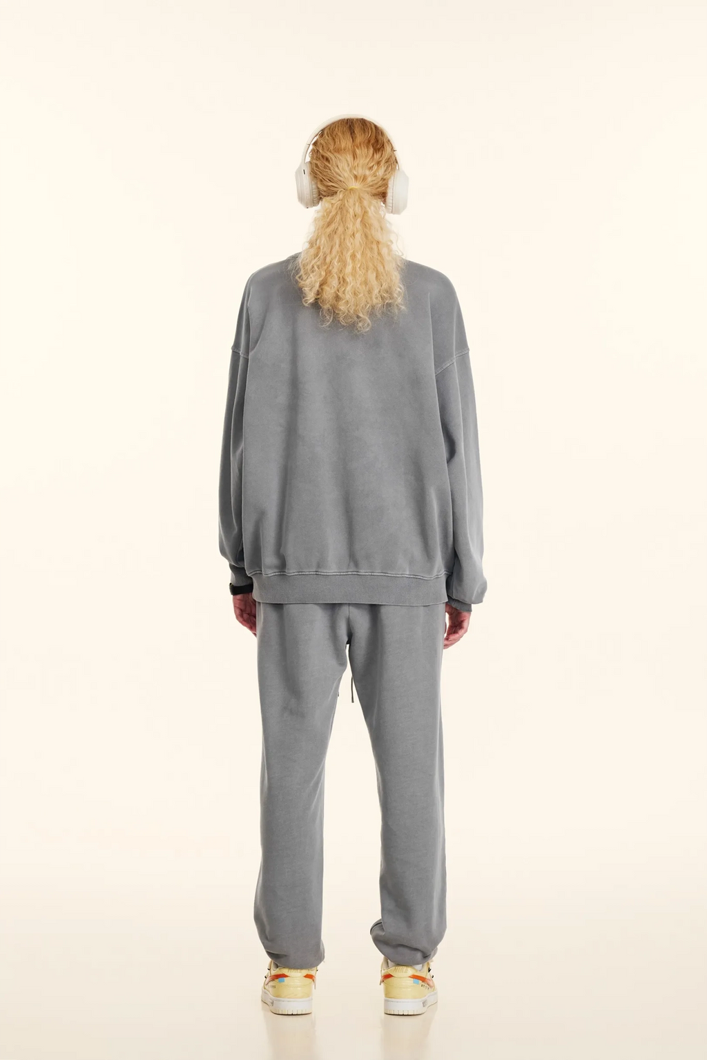 Person wearing a gray tracksuit on a white background