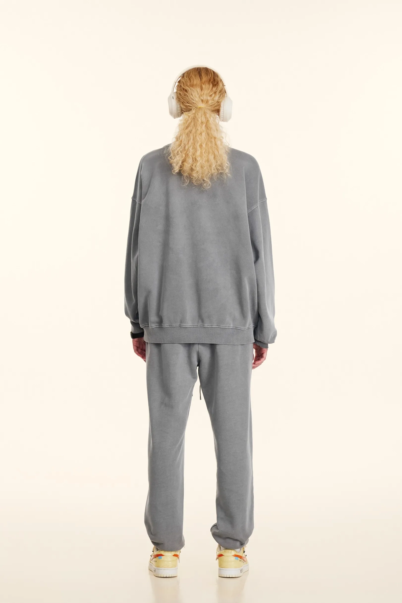 Person wearing a gray tracksuit on a white background