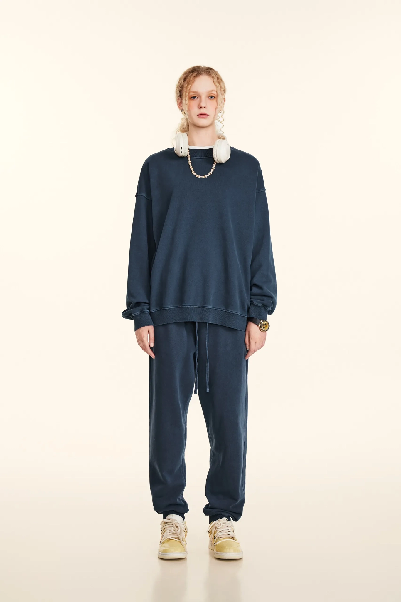 Person wearing a navy blue outfit with beige shoes on a white background