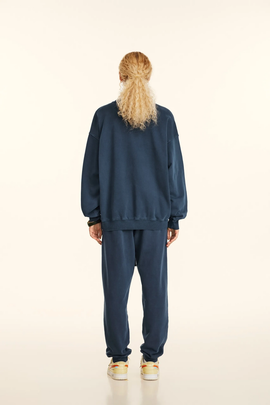 Person wearing a blue tracksuit on a beige background