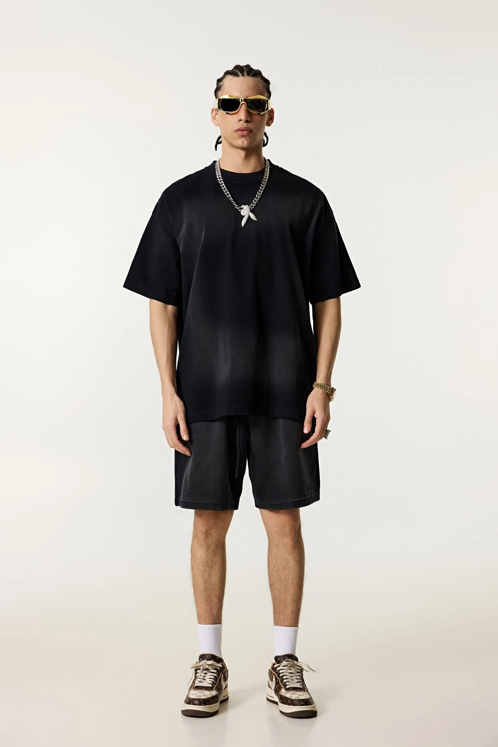 Person wearing a black outfit with sunglasses on a white background