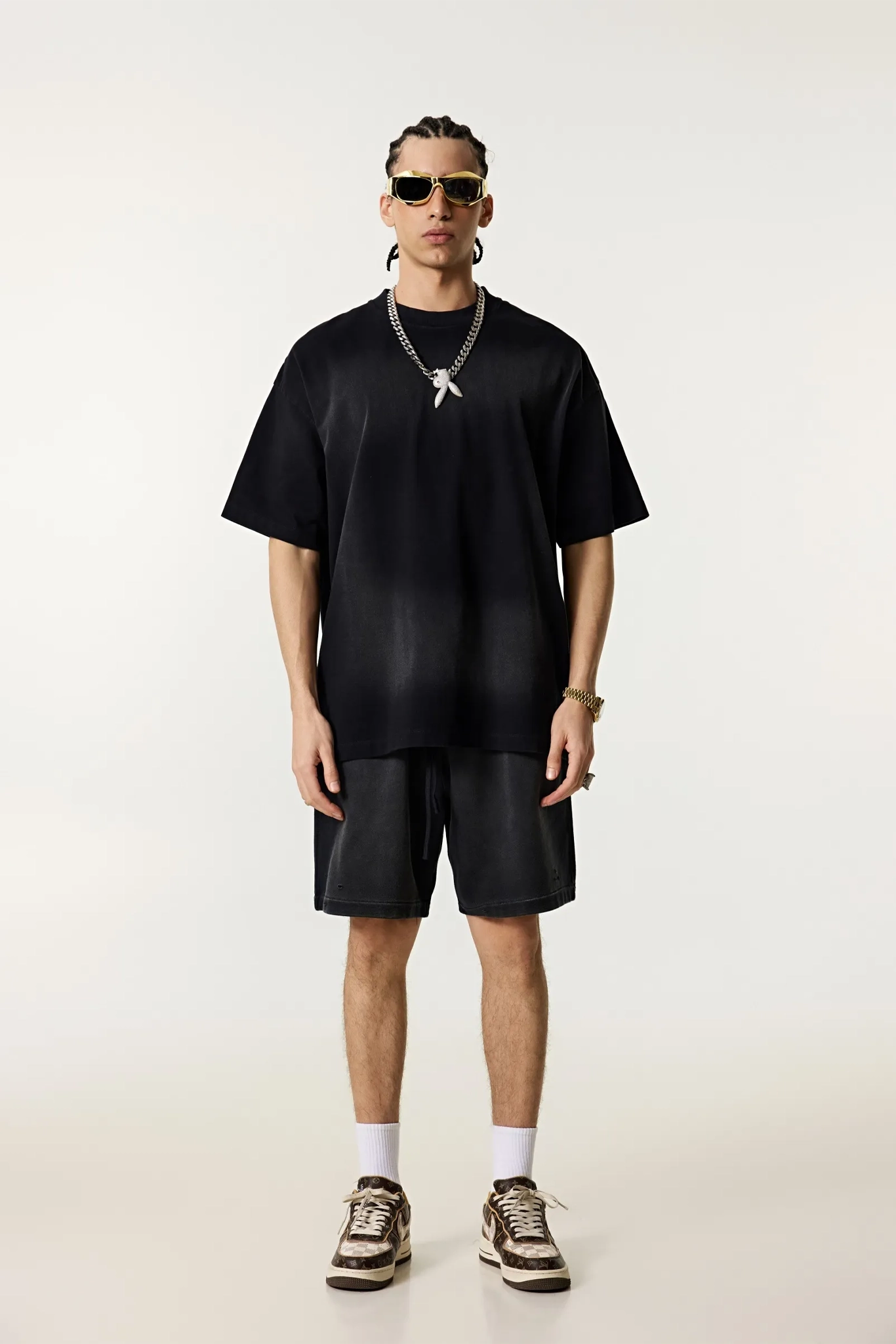 Person wearing a black outfit with sunglasses on a white background