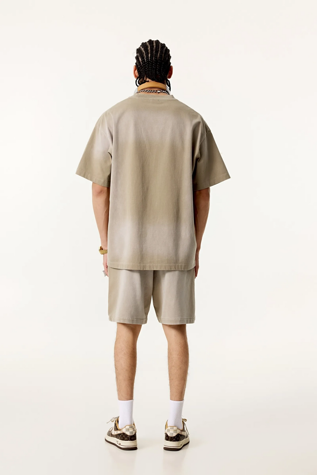 Person wearing a beige shirt and shorts set on a white background