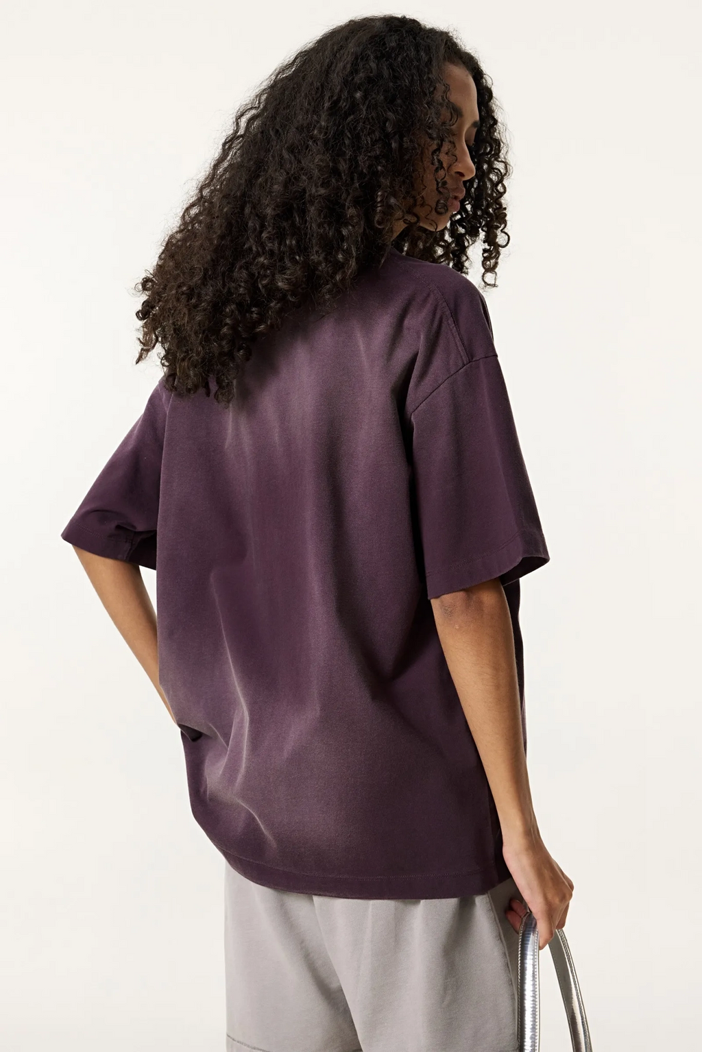 Person wearing a purple oversized shirt and light gray pants on a white background