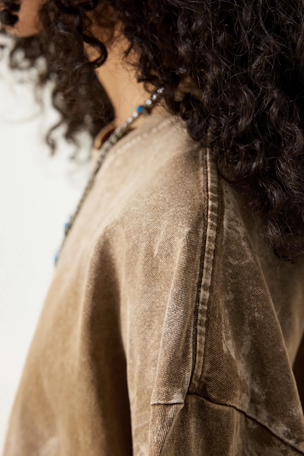 Close-up of a person wearing a beige jacket with a blurred background