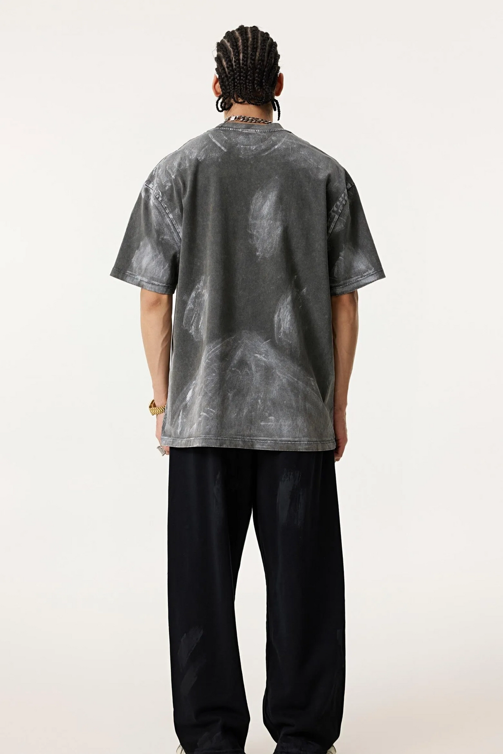 Person wearing a gray tie-dye t-shirt and black pants on a white background