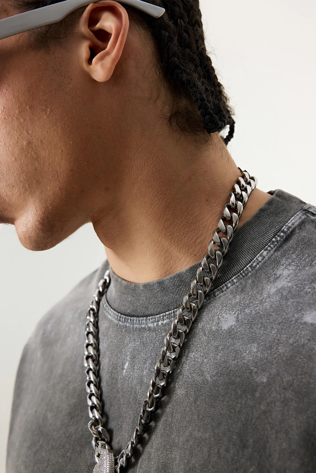 Person wearing a chain necklace and gray sweatshirt against a neutral background