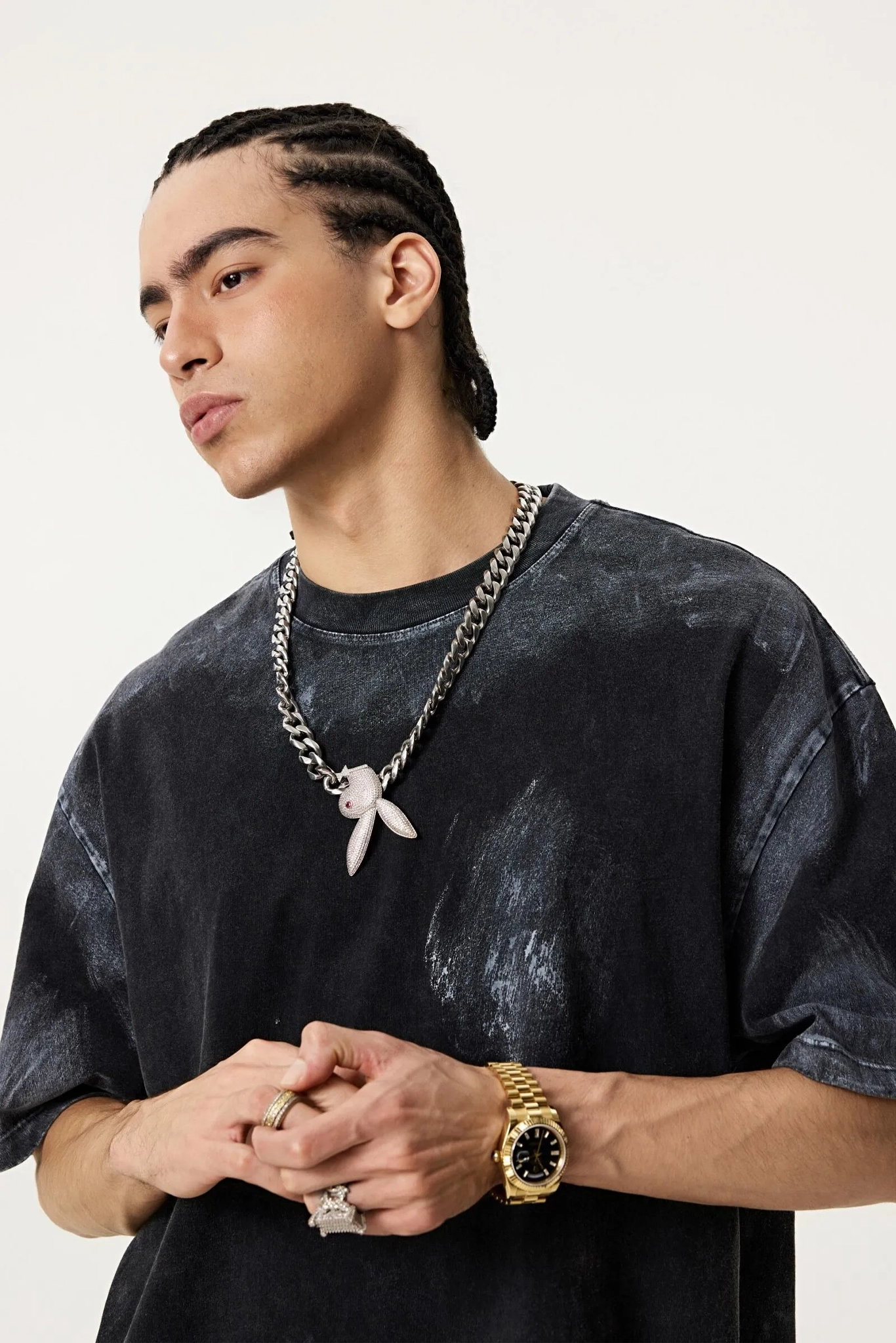 Man wearing a black shirt, gold watch, and chain necklace on a white background