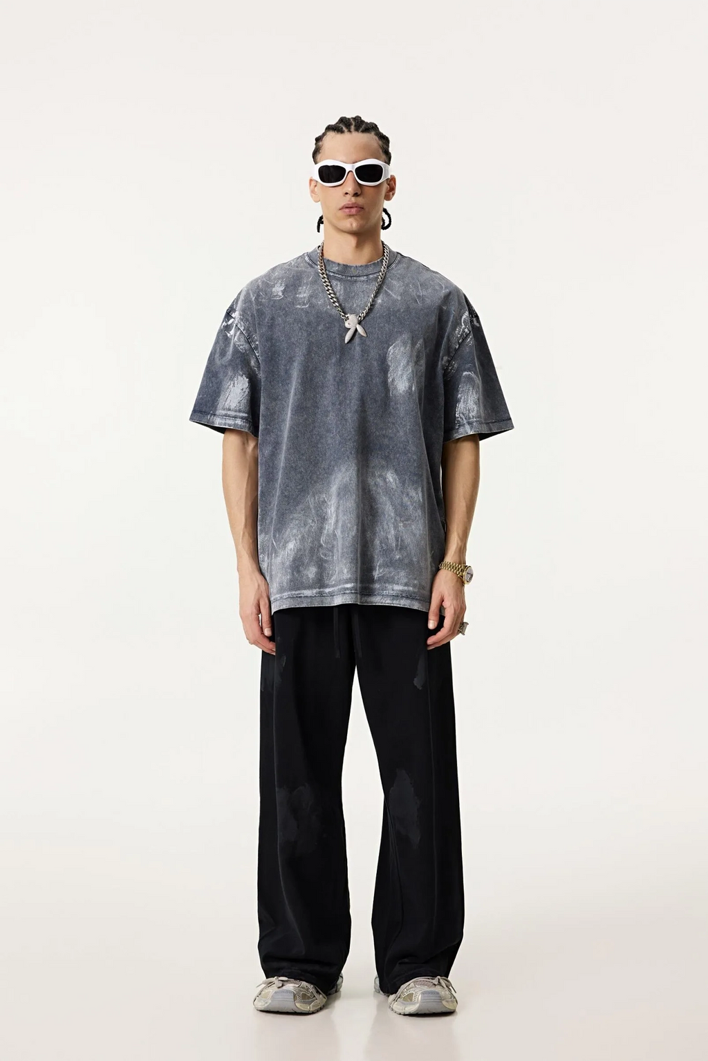 Person wearing a tie-dye t-shirt and black pants on a white background