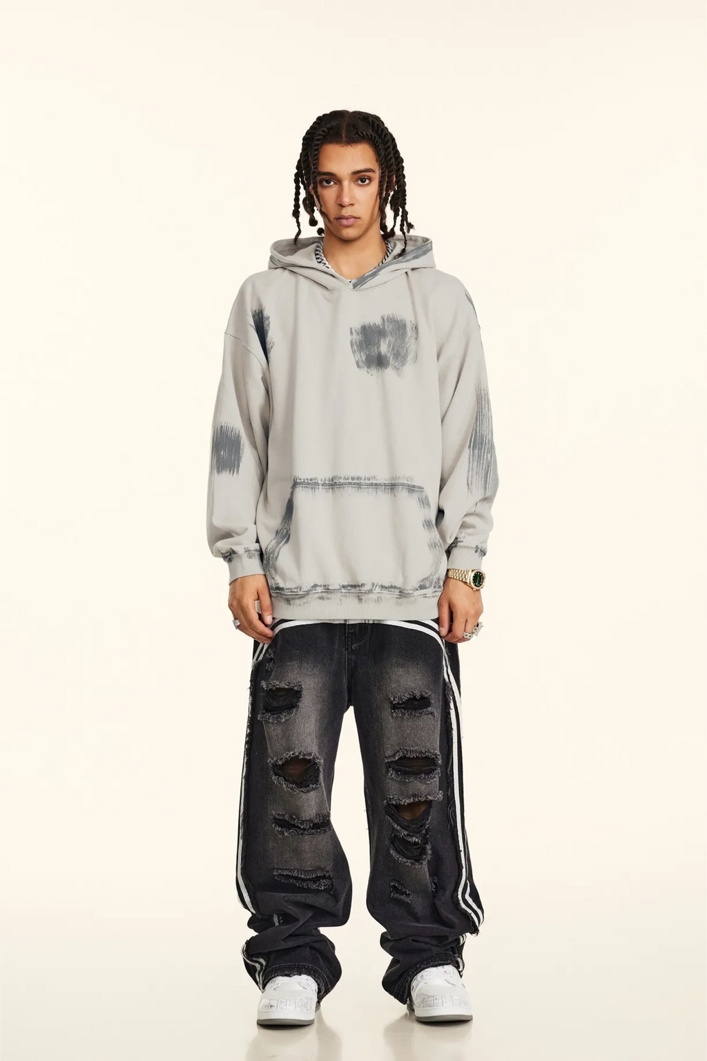 Person wearing a gray tie-dye hoodie and distressed jeans on a white background