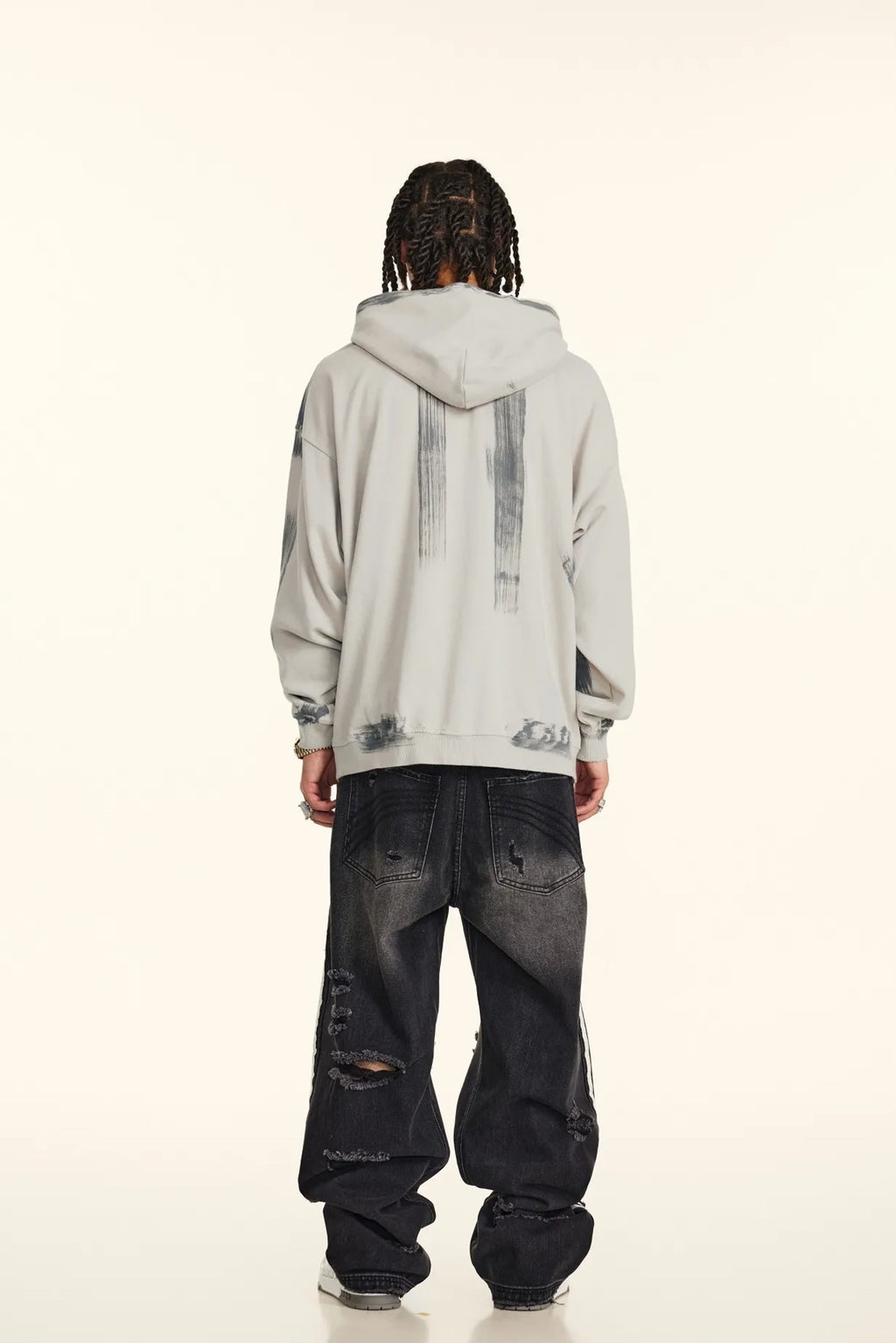 Person wearing a light gray hoodie and dark jeans on a white background