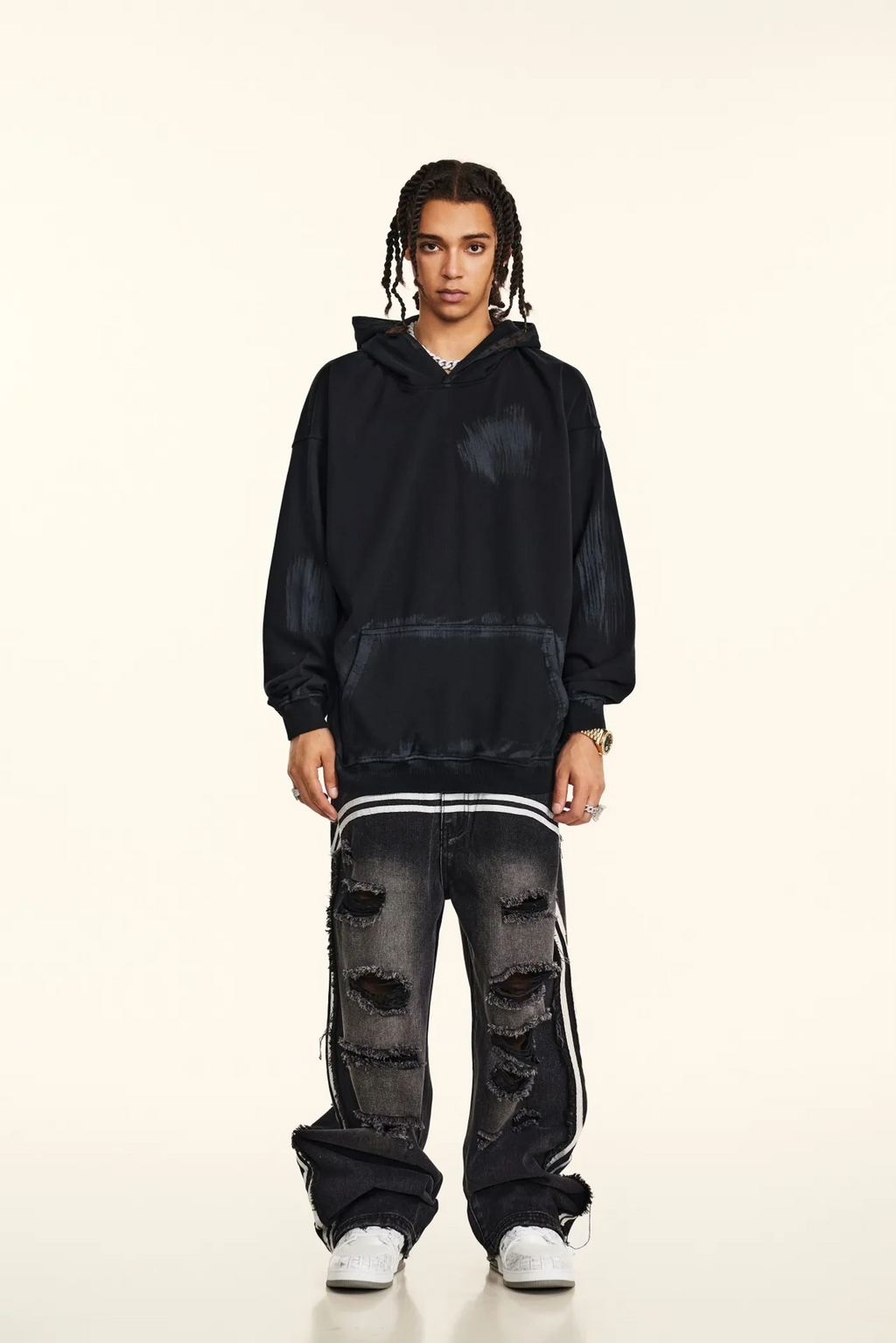 Person wearing a black hoodie and distressed jeans on a white background