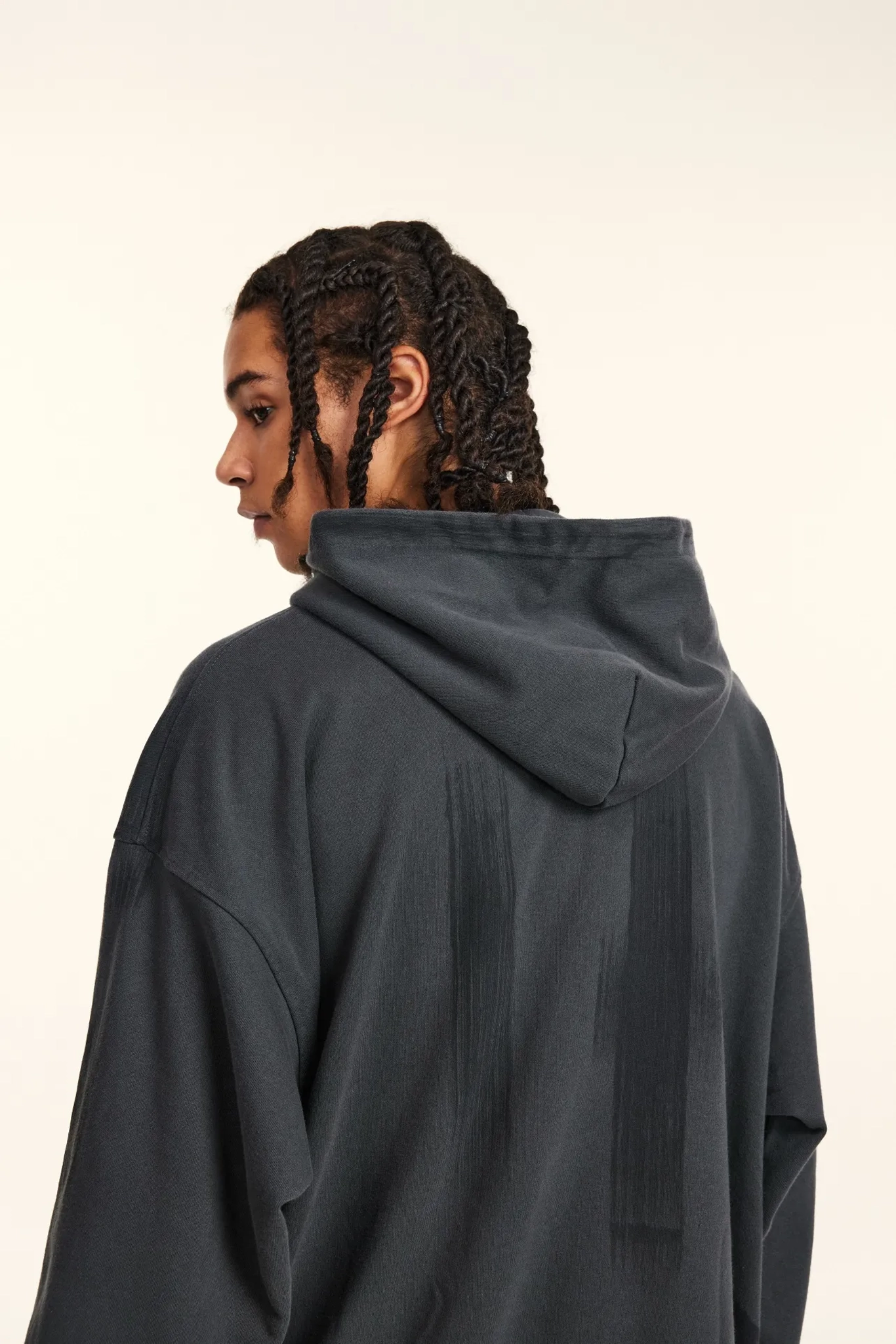 Person wearing a dark gray hoodie from behind on a white background