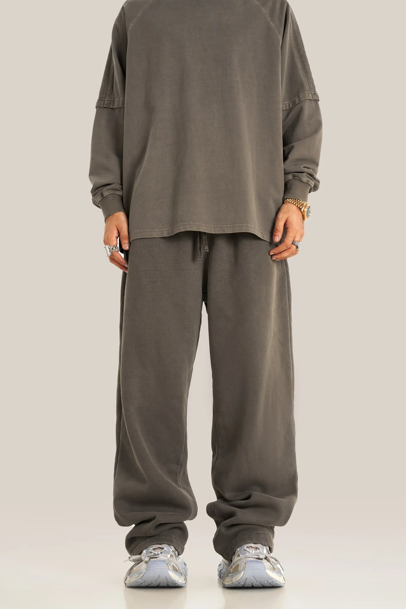 Person wearing a gray outfit with wide-leg pants on a plain background