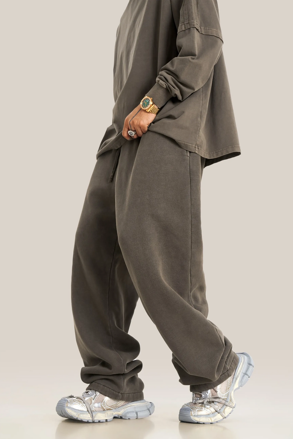 Person wearing a gray outfit with silver shoes on a plain background