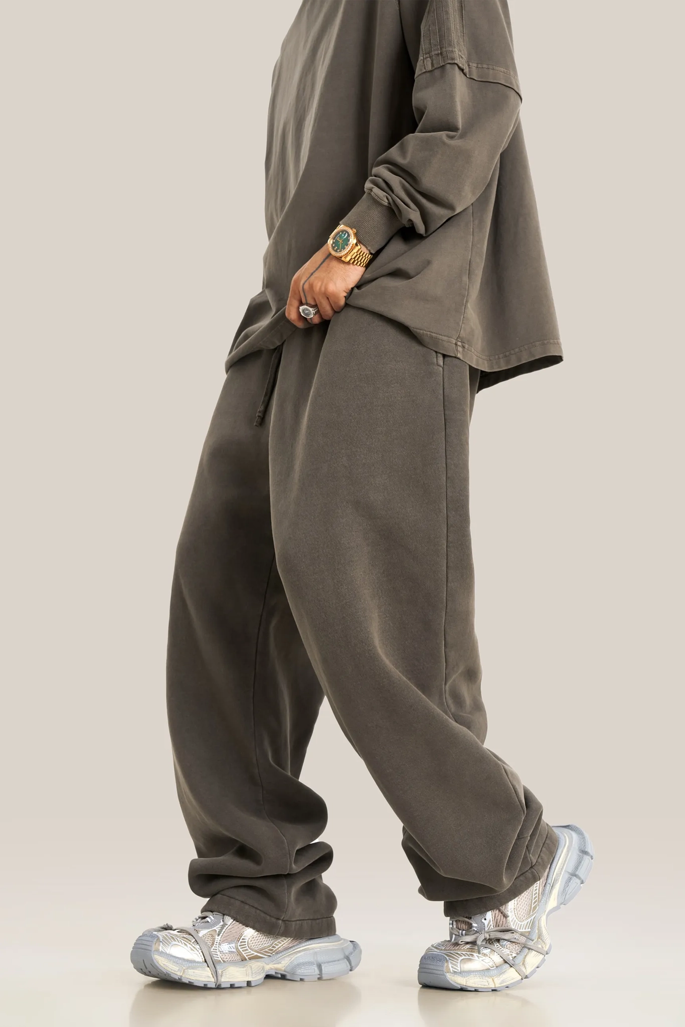 Person wearing a gray outfit with silver shoes on a plain background