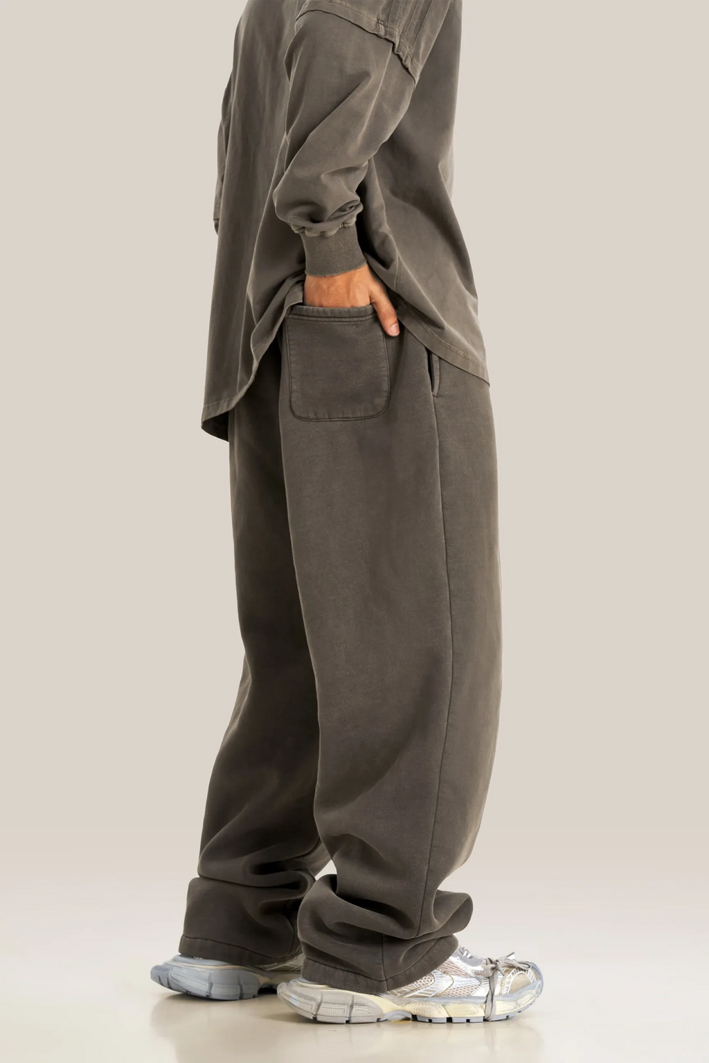 Person wearing a gray oversized outfit with matching pants on a beige background