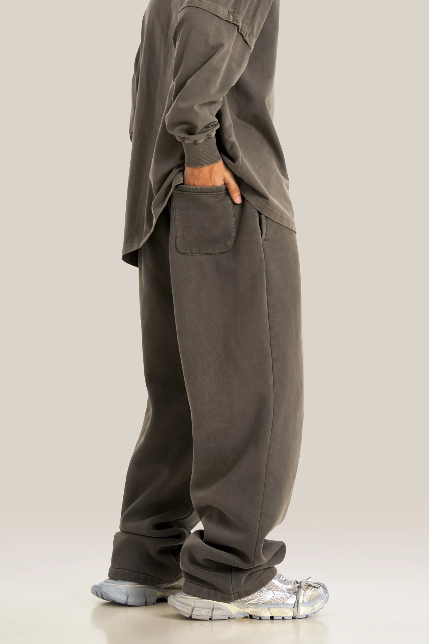 Person wearing a gray oversized outfit with matching pants on a beige background