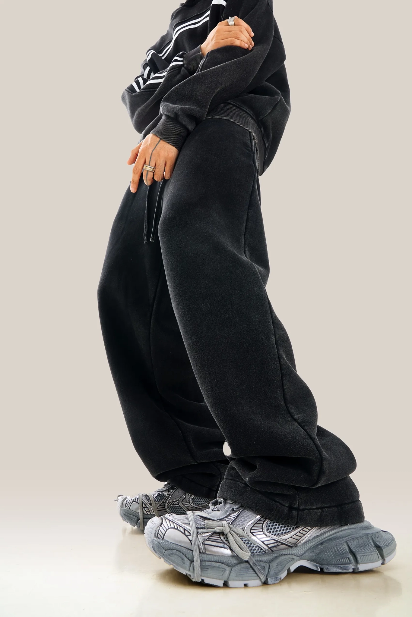 Person wearing black oversized pants and gray sneakers on a neutral background